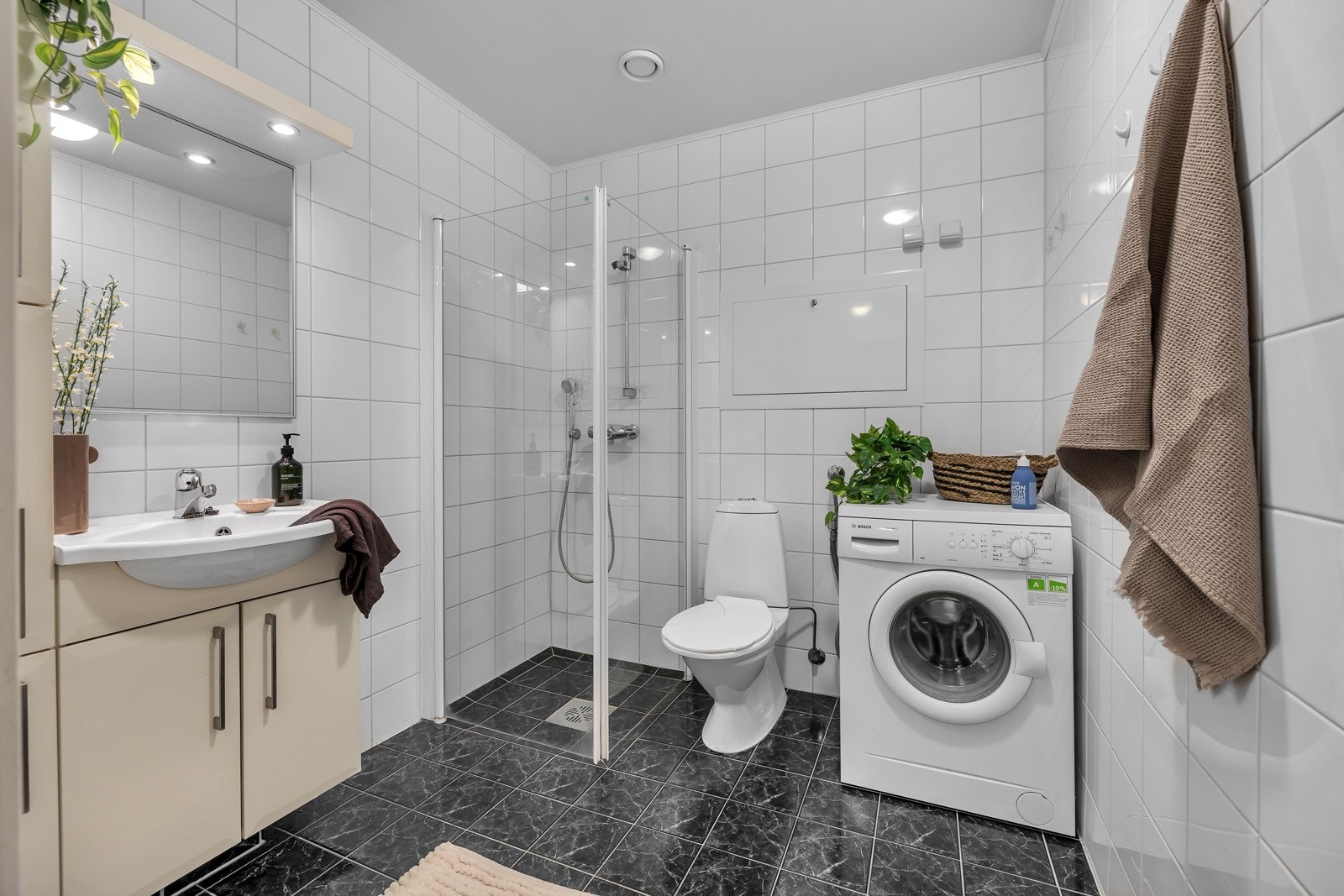 Praktisk bad med fliser både på gulv og vegger. Innredning med god lagringsplass og opplegg for både vaskemaskin og tørketrommel Galleribilde