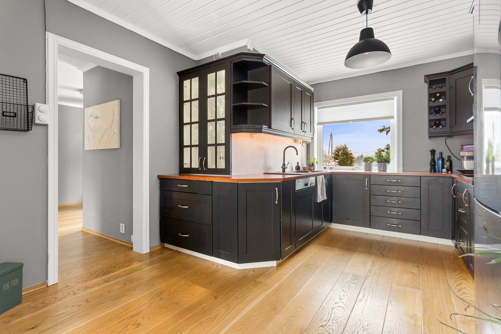 Delvis åpen kjøkkenløsning med integrerte hvitevarer. Fra kjøkkenet er det utsikt mot hagen. Galleribilde