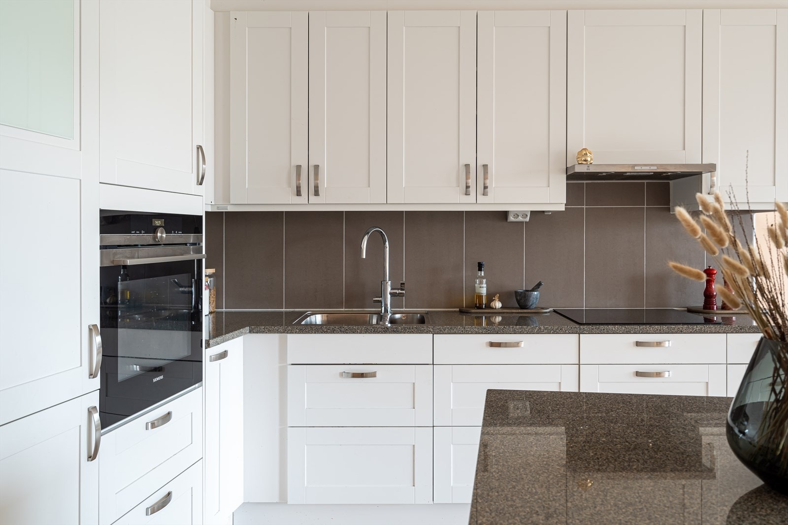 Kjøkken med benkeplate i stein og rikelig med oppbevaringsplass. Galleribilde