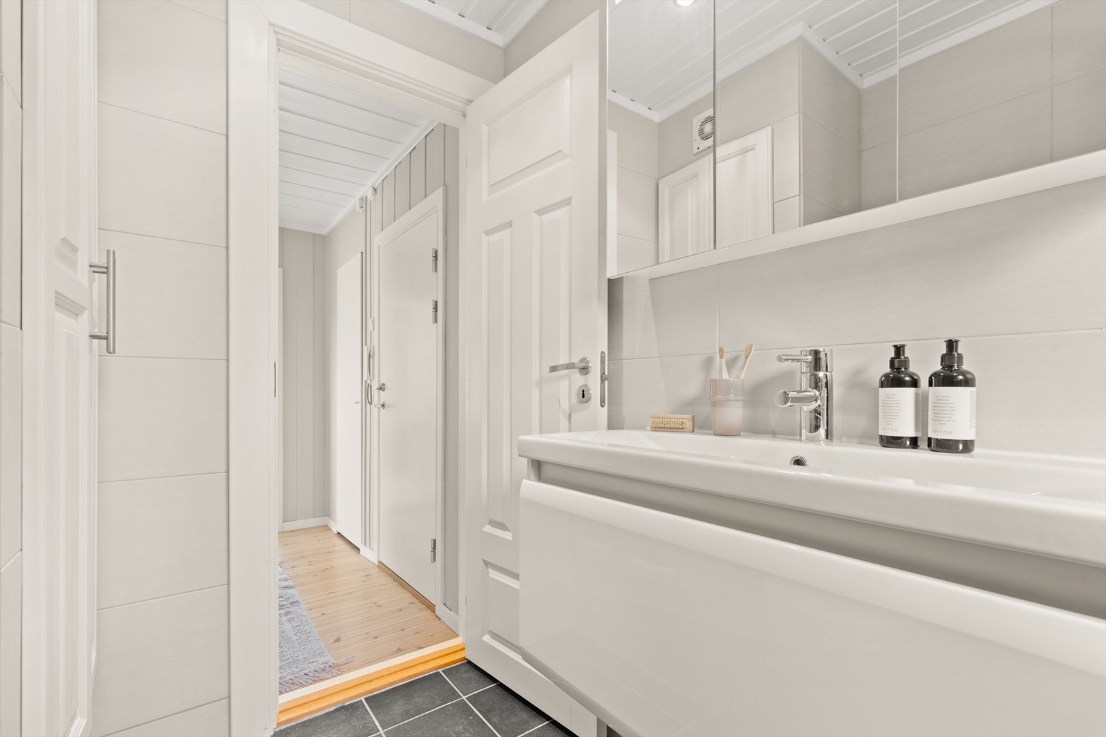 På badet er det grå fliser med gulvvarme, hvite veggfliser og downlights i himling. Galleribilde