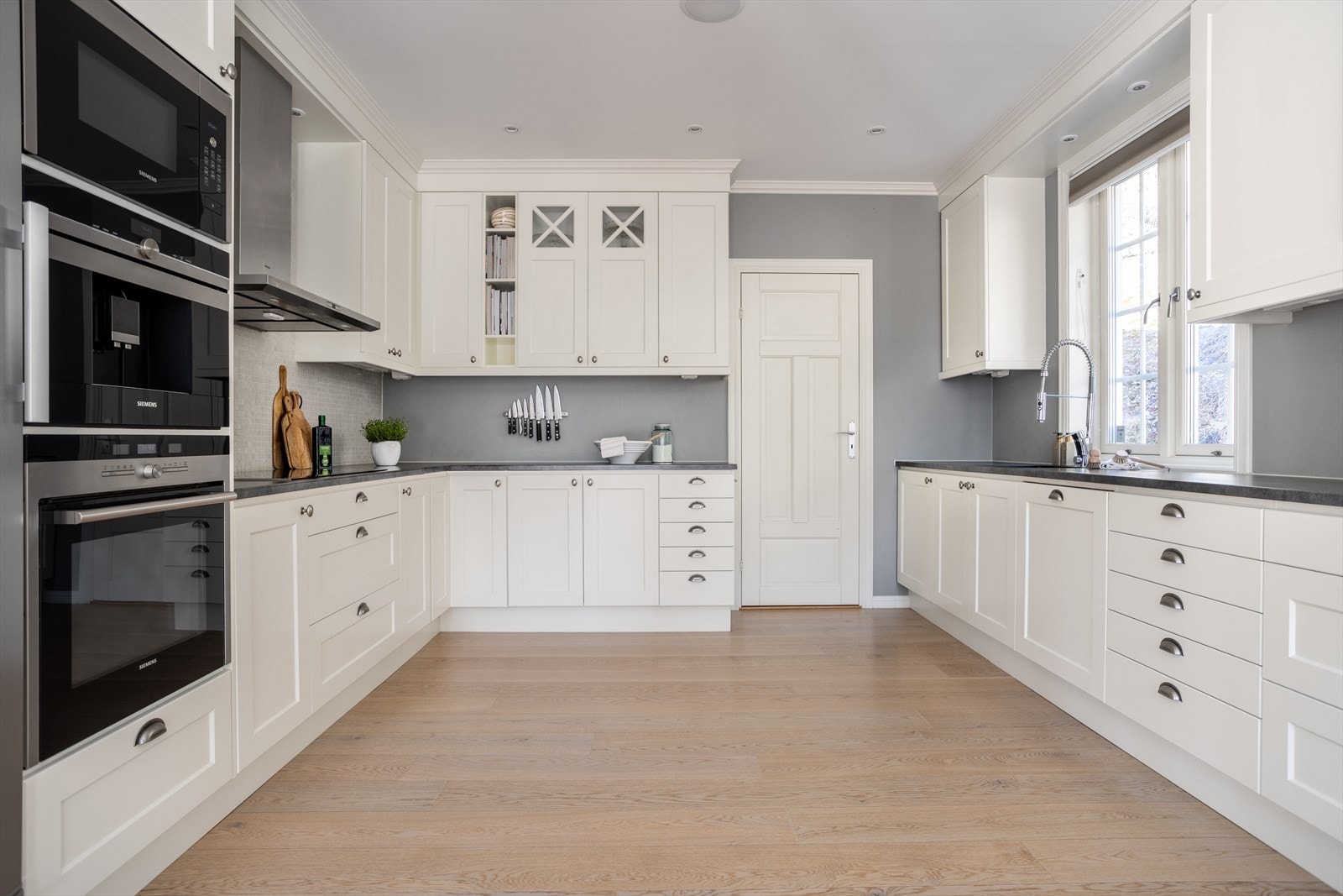 Innredningen består av hvite, profilerte fronter, laminat benkeplate og stålhåndtak. Galleribilde