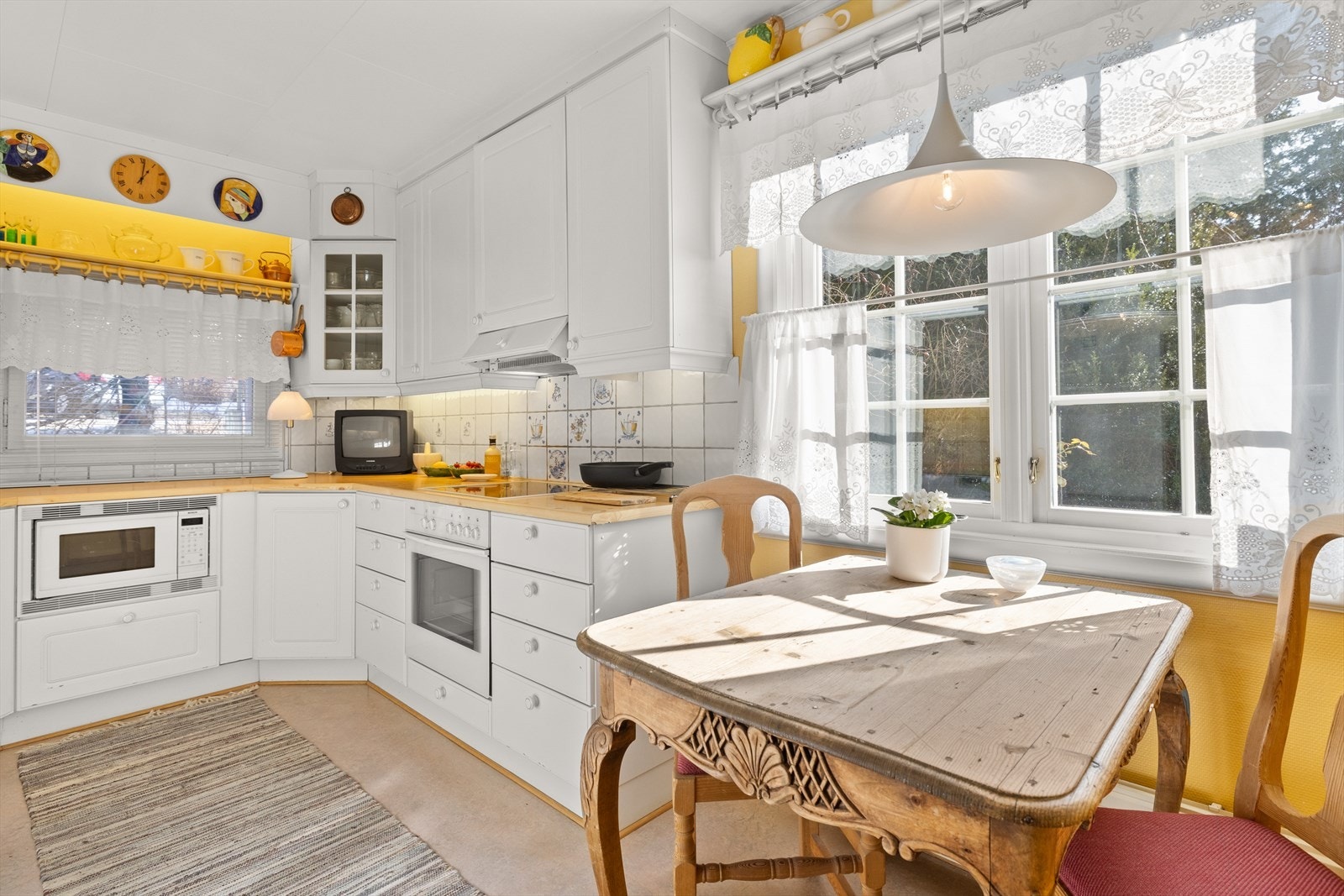 Kjøkkeninnredning med profilerte fronter. Belysning under overskap. Fliser på vegg over benkeskap. Laminat benkeplate med nedfelt kum i rustfritt stål Galleribilde