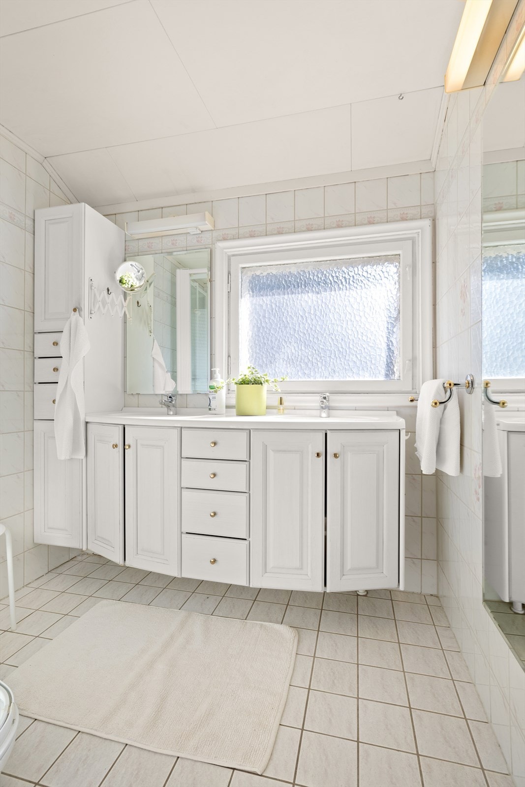 Badet har dobbel servant, dusjkabinett og fliser på gulv og vegg Galleribilde