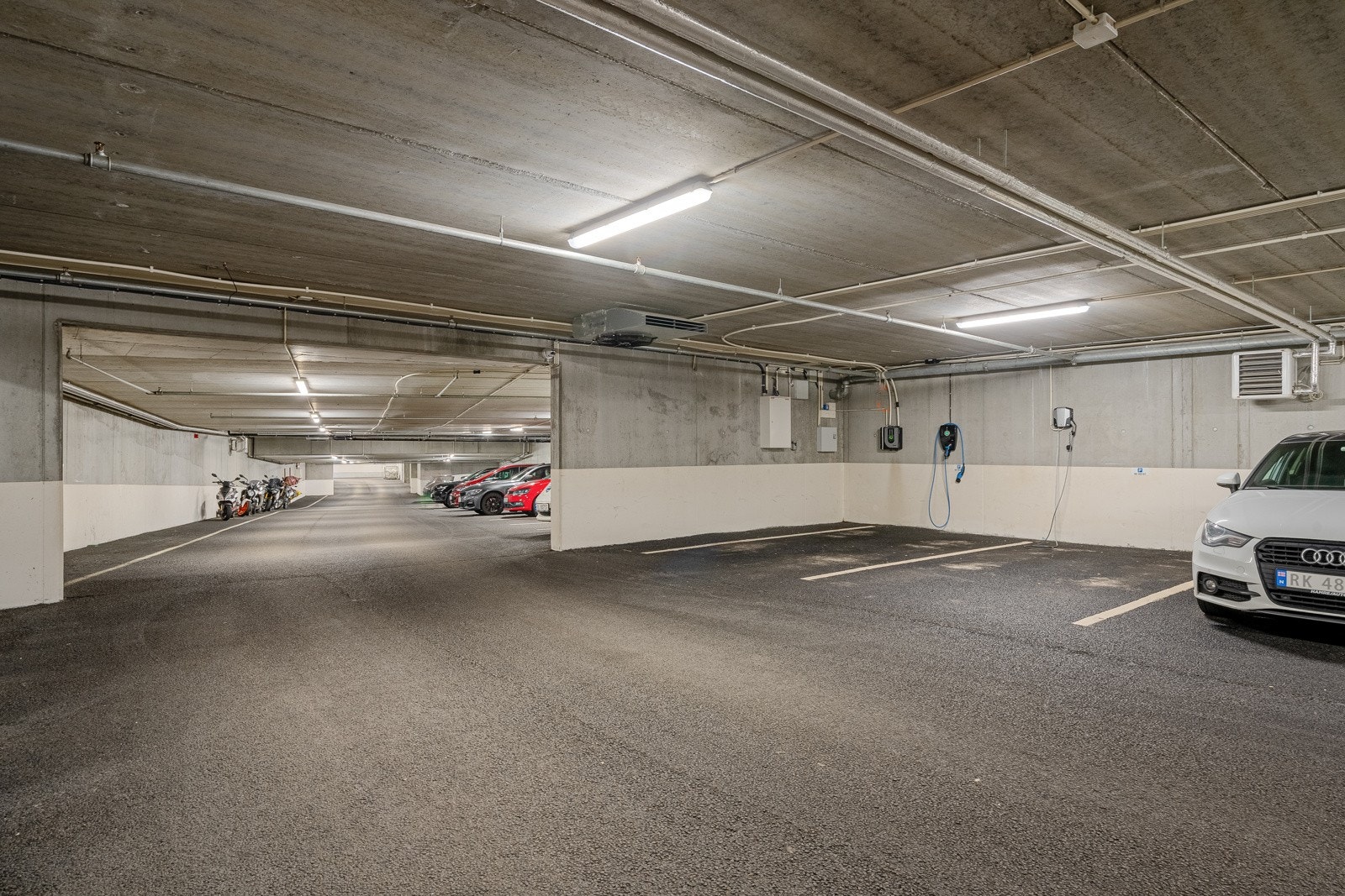 Biloppstillingsplass i underetasjen. El-bil lader installert. Galleribilde