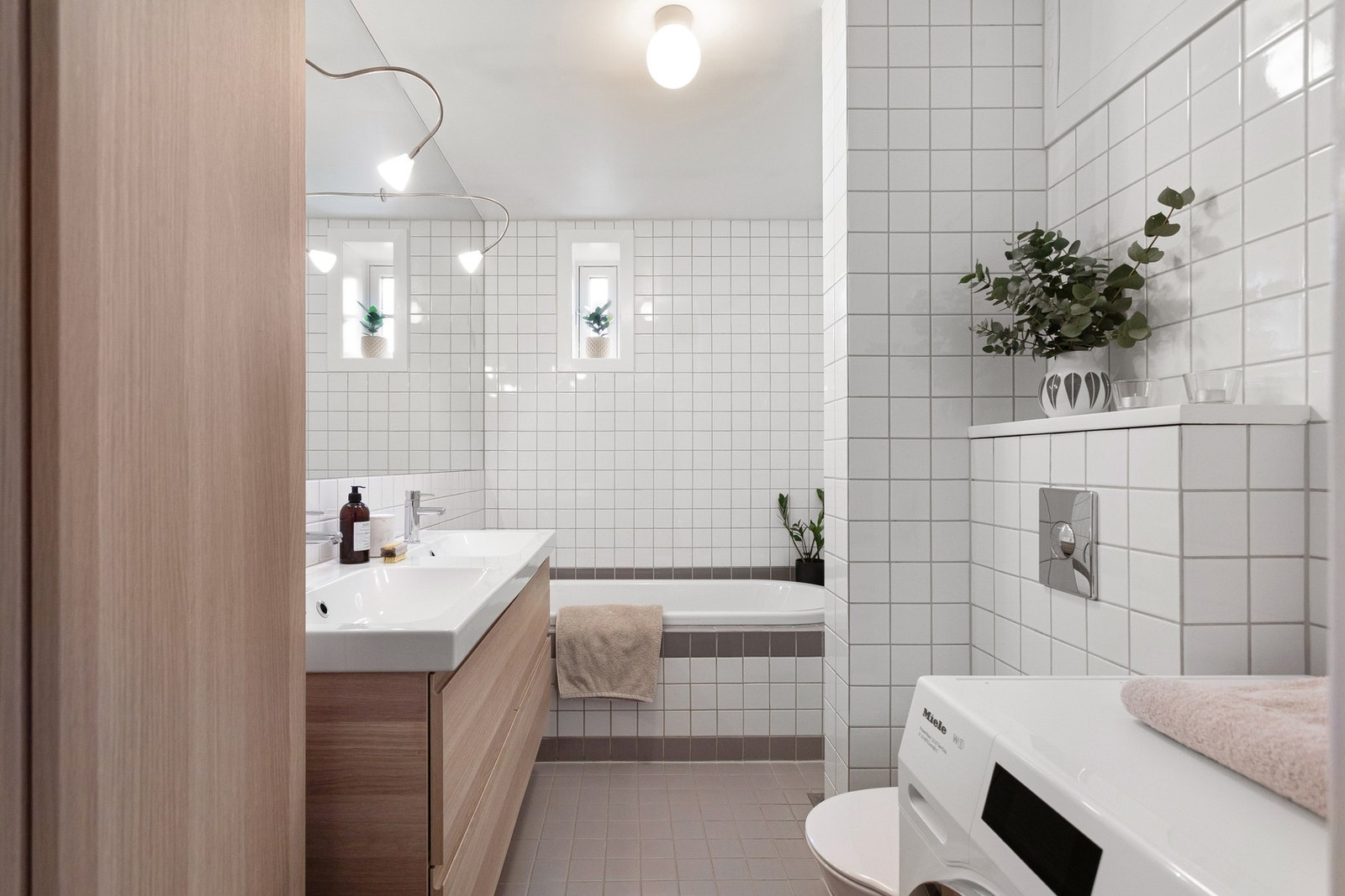 Leiligheten har et lyst flislagt baderom fra 2004. Baderommet har grå fliser på gulv med gulvvarme og hvite fliser på veggene. Galleribilde