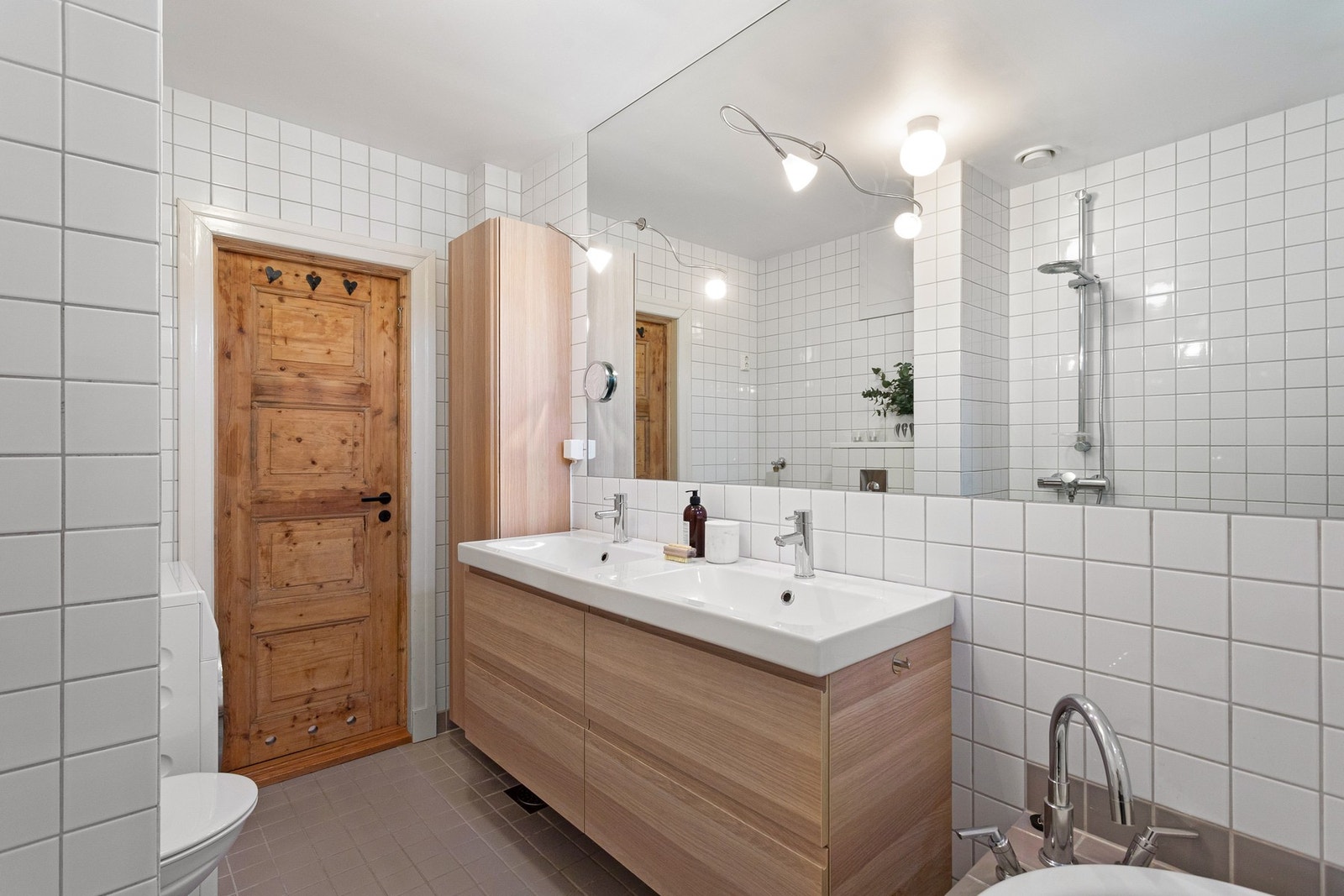 Nyere og moderne baderomsinnredning fra 2019 med skuffer og heldekkende dobbelservant, stort speil med belysning over. Galleribilde