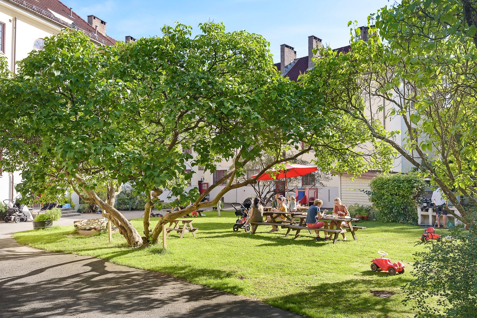 De indre gårdsrommene som oppleves som en oase av borettslagets beboere. Representativt og ryddig med prydbusker, plener, sittegrupper og brosteinsbelagte gangveier. Barnevennlig, med egen lekeplass for barna. (arkivbilde) Galleribilde