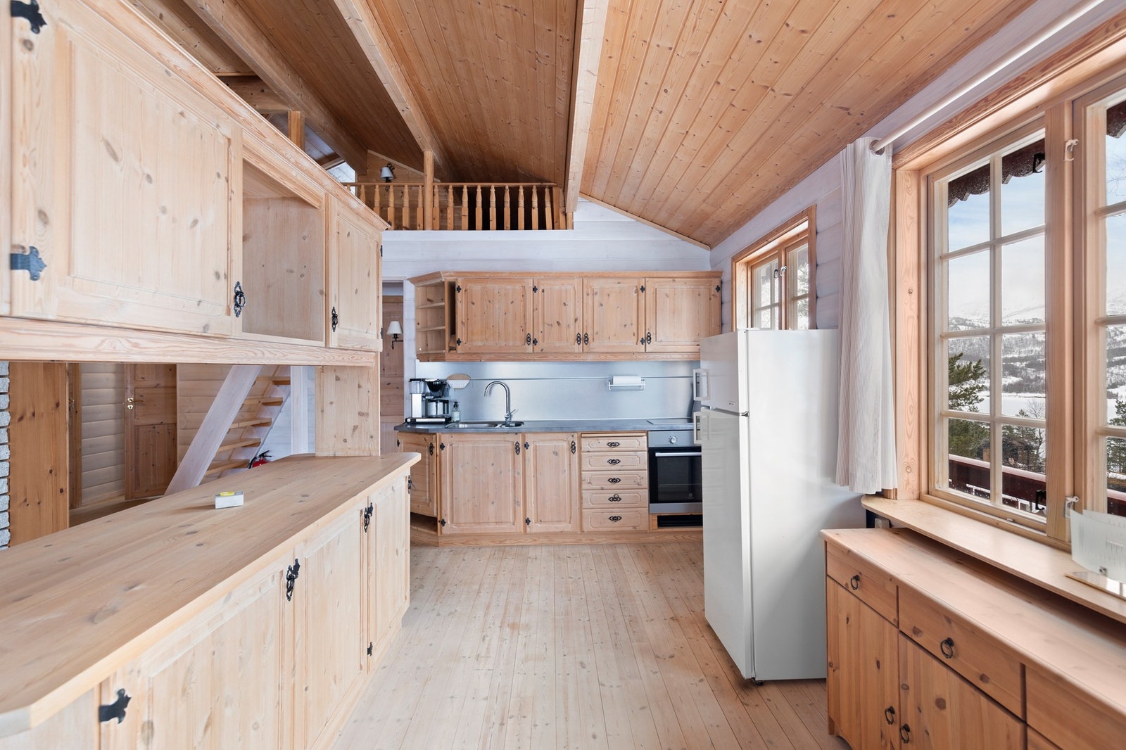 Kjøkkenet har montert en I-formet furuinnredning med benkeskap og overskap Galleribilde