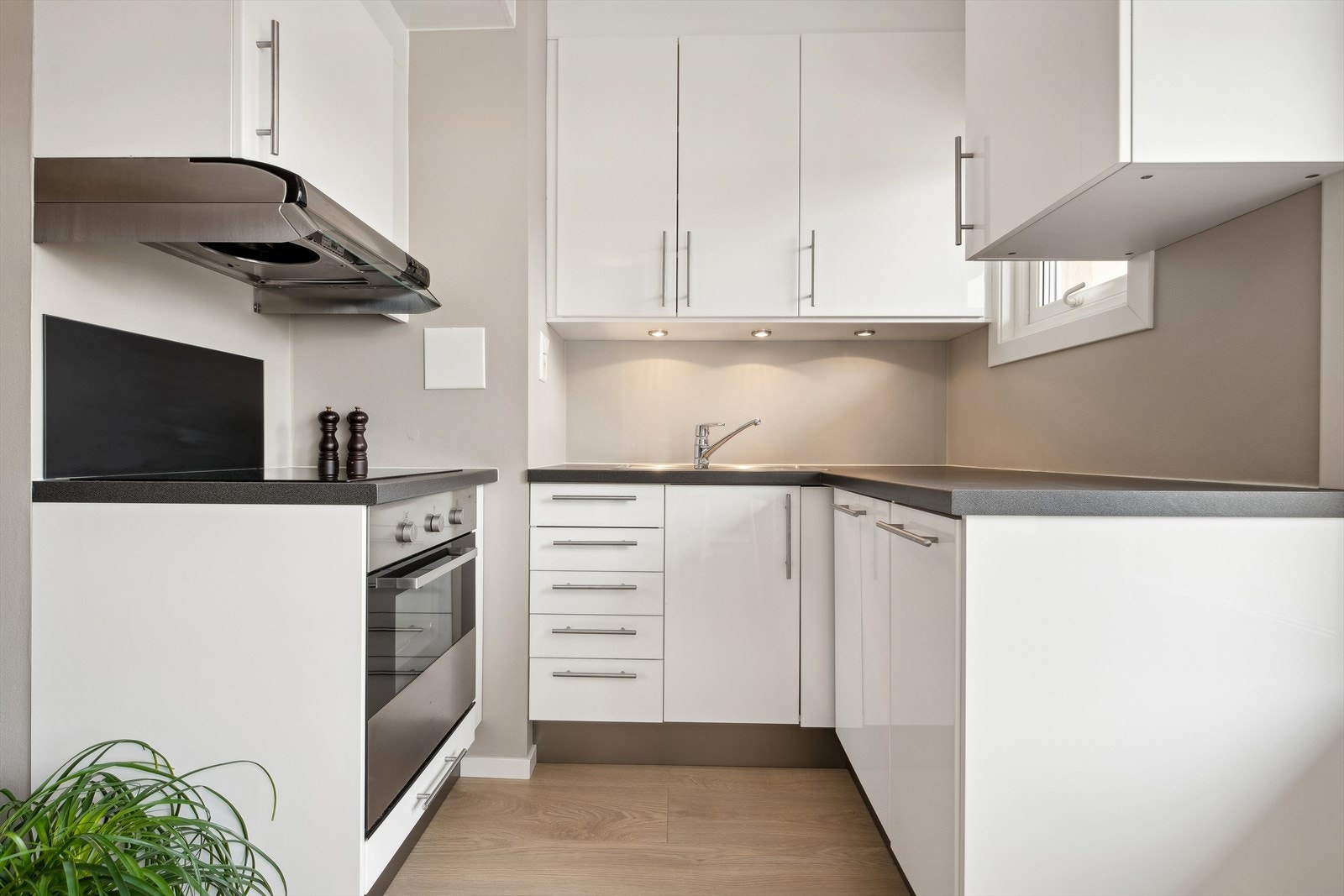 Kjøkkenet i hvit utførelse har moderne utrykk med spotter under skap Galleribilde