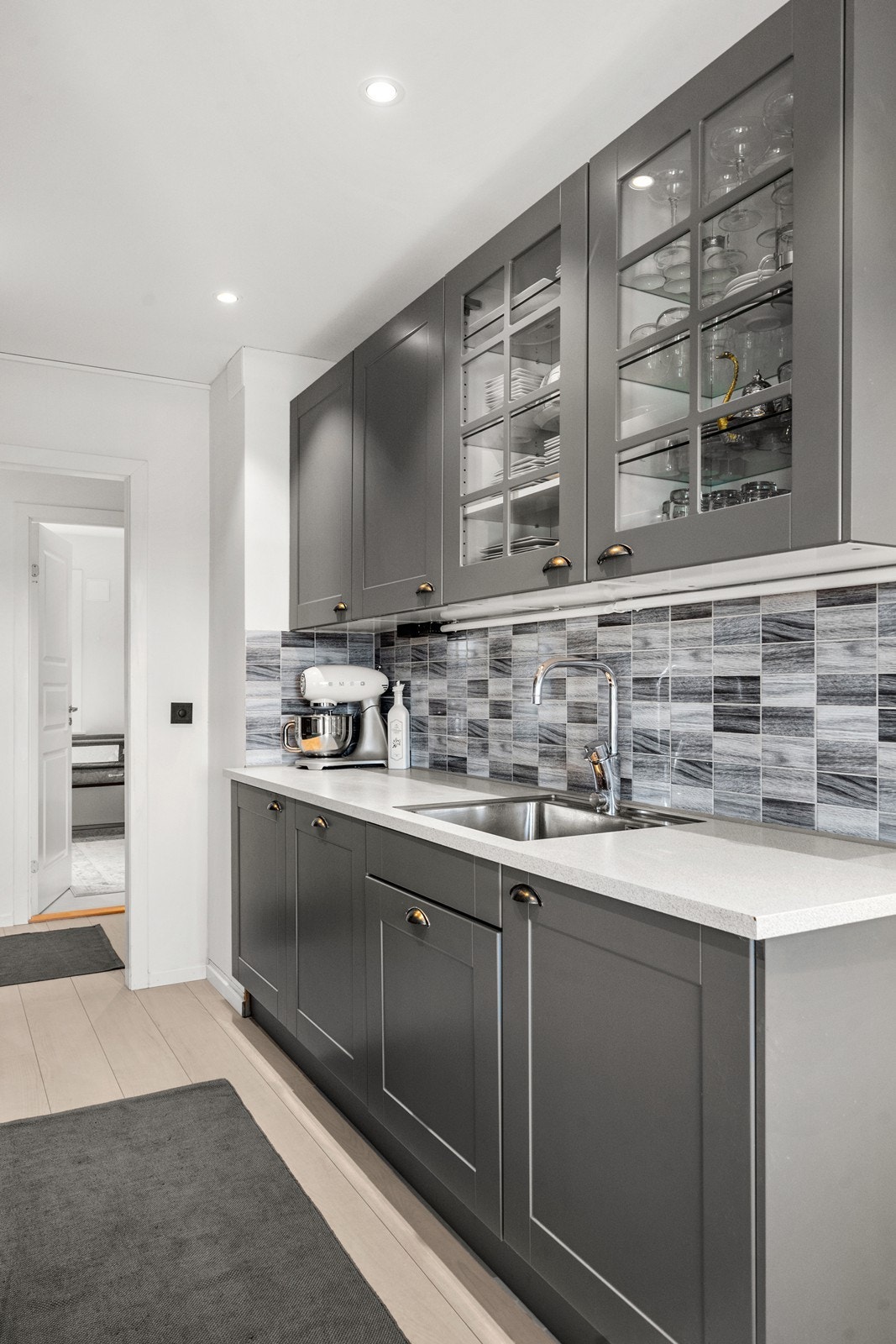 I innredningen er det integrerte hvitevarer som mikro og stekeovn i ståhøyde, platetopp, oppvaskmaskin og kjøle-/fryseskap. Fliser pryder og beskytter bakveggene og ventilatoren har kullfilter. Galleribilde