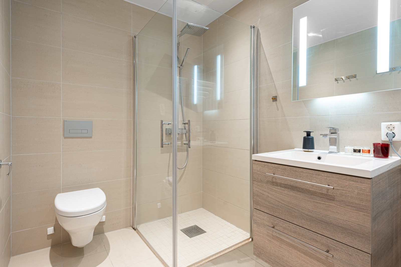 Badet er utsyrt med dusj med innfellbare glassvegger, regnfallsdusj, servantseksjon med skuffer og heldekkende komposittvask, speil med lys, vegghengt wc og opplegg for vaskemaskin/tørketrommel. Galleribilde