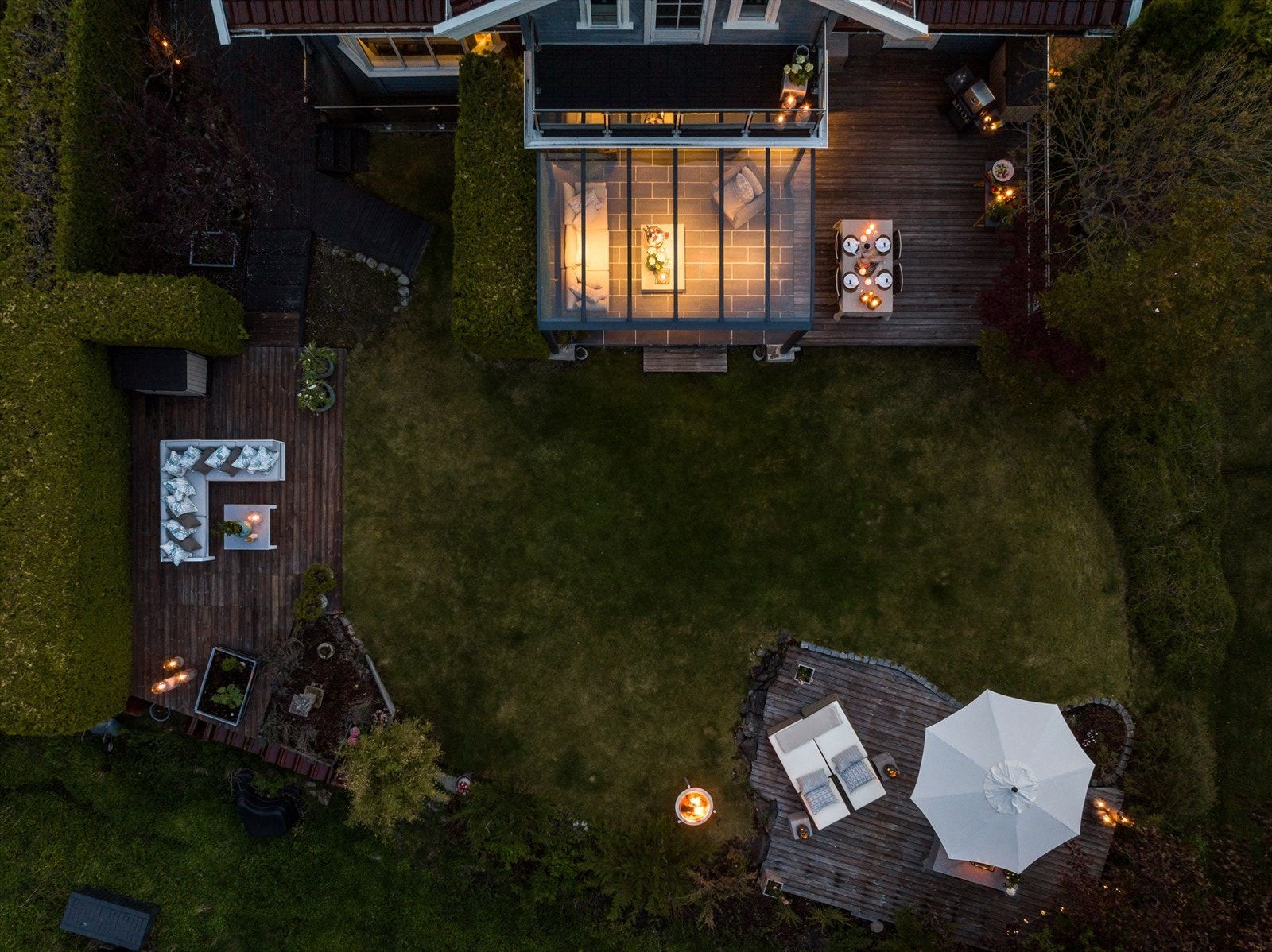 Stemningsfullt kveldsbilde av overbygd terrasse og hage. Her kan en nyte sene sommerkvelder. Galleribilde