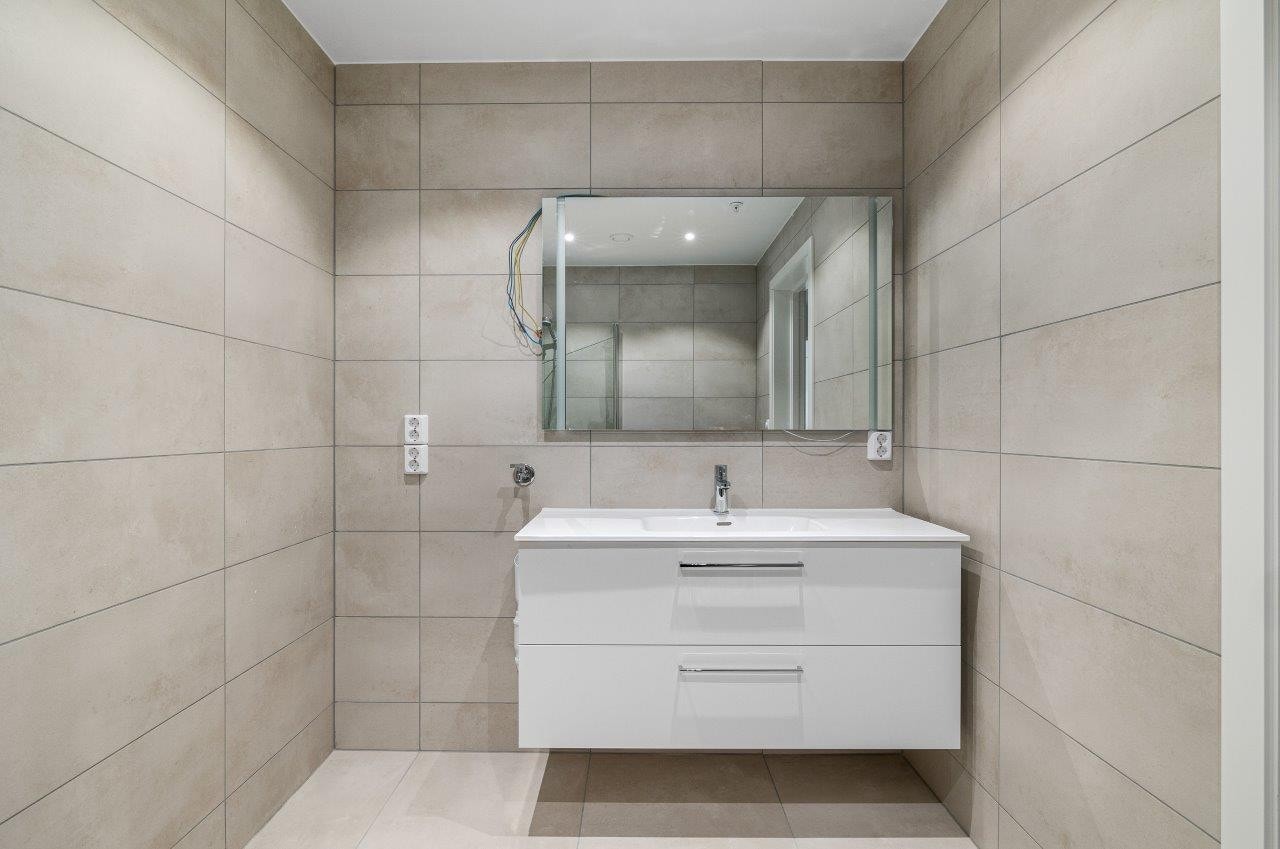 Lekkert flislagt baderom med downlights. Lekkert speil med integrert lys Galleribilde