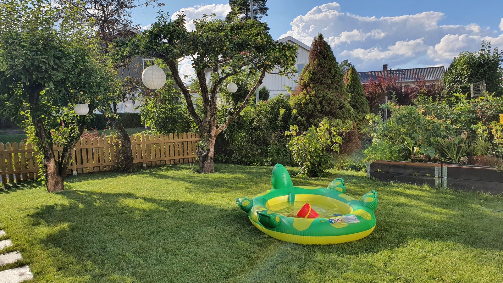 Koselig og lettstelt hage med epletær, plantekasser og bærbusker (blåbær, jordbær, stikkelsbær og rips). Galleribilde