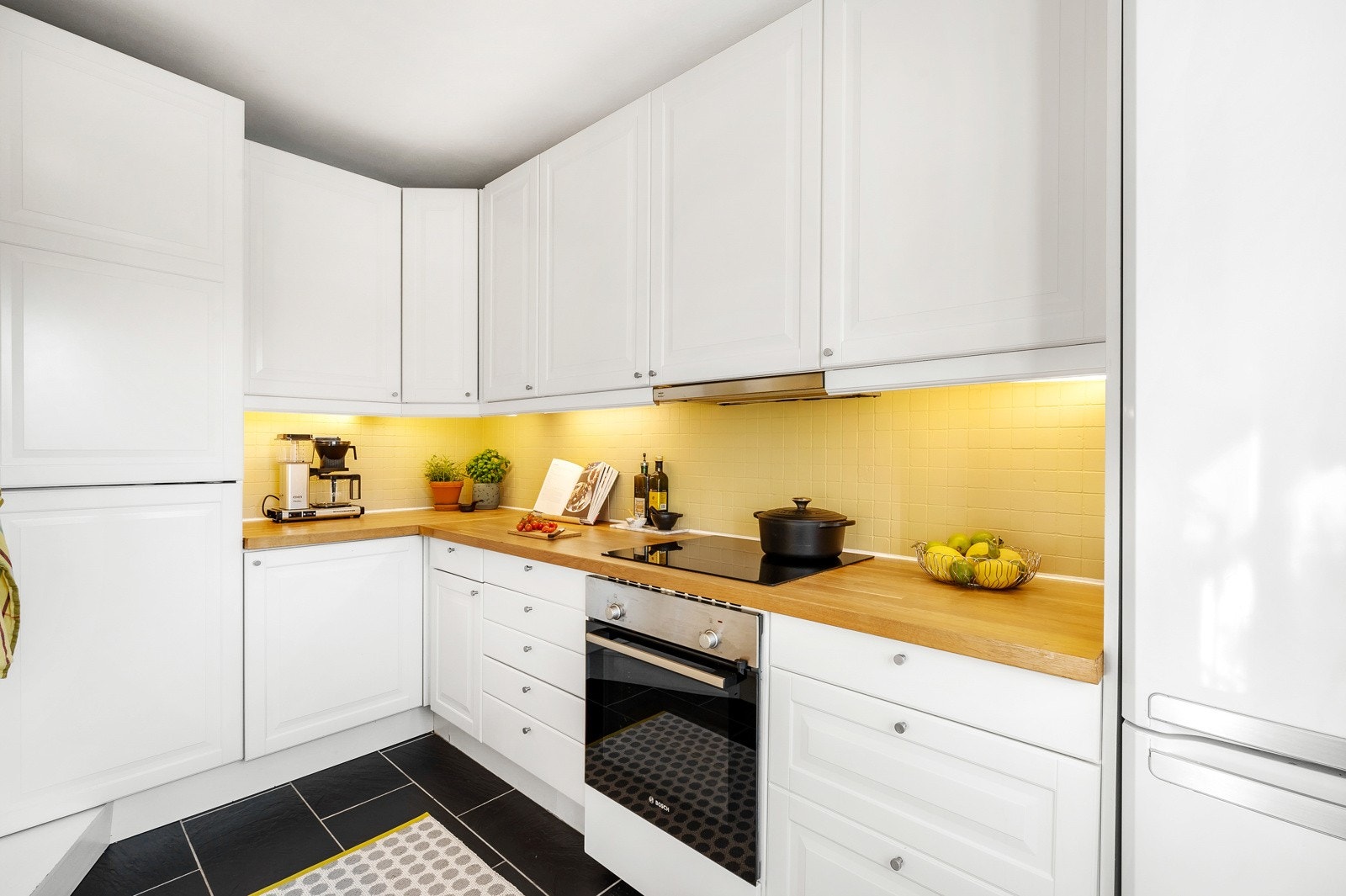 Kjøkkeninnredningen har profilerte fronter i tidløs stil, benkeplate av tre og fliser på vegg over kjøkkenbenk. Galleribilde