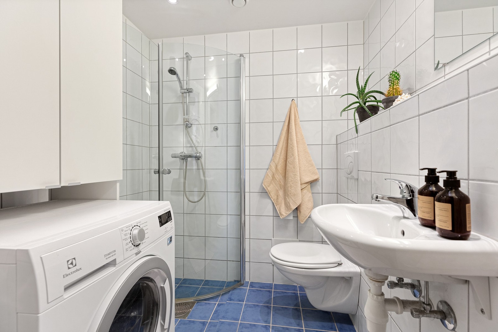 Flislagt bad med dusjhjørnet og opplegg for vaskemaskin. Galleribilde