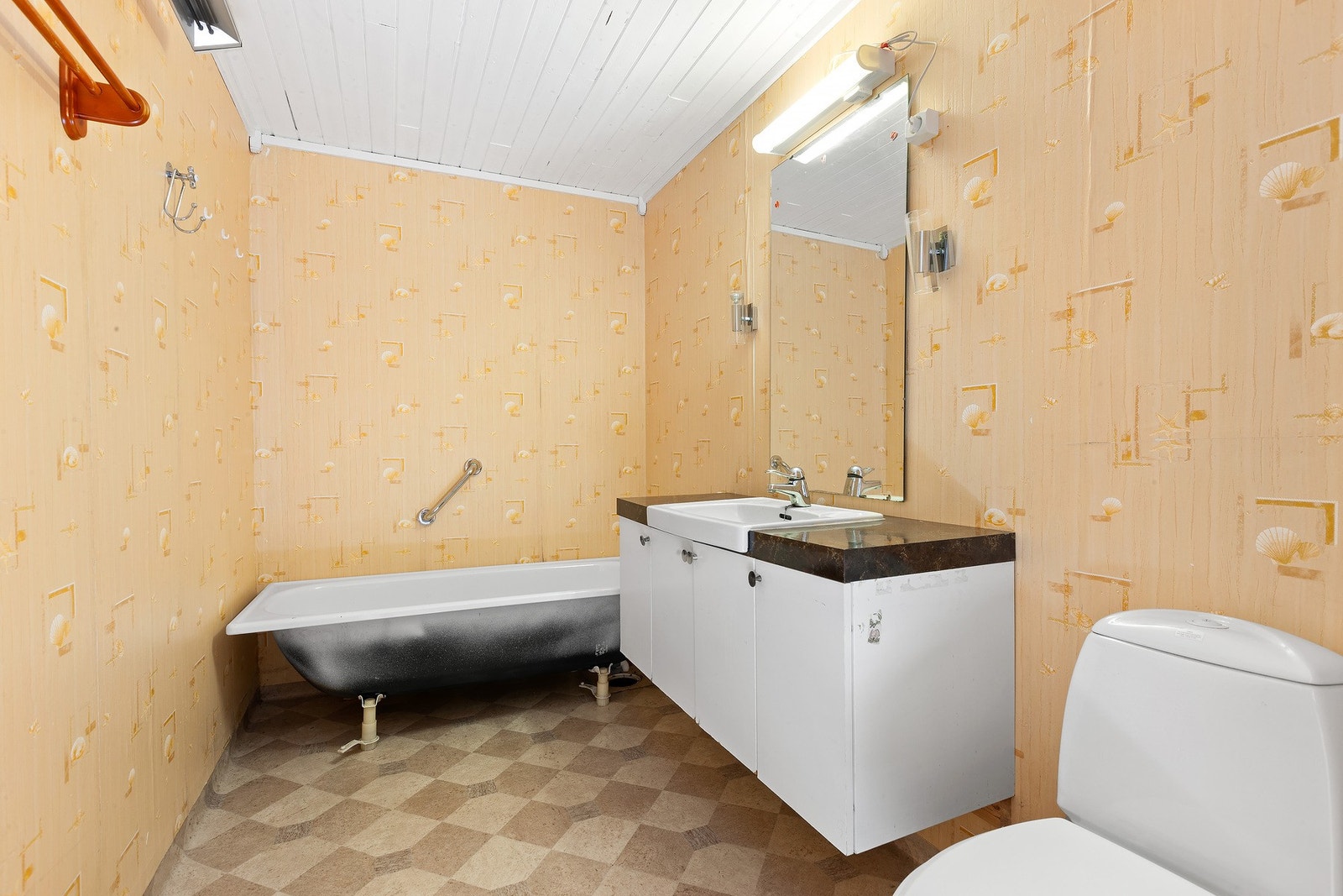 Bad kjeller har lys innredning med nedfelt servant og skap under, speil med lys over, badekar og toalett. Galleribilde