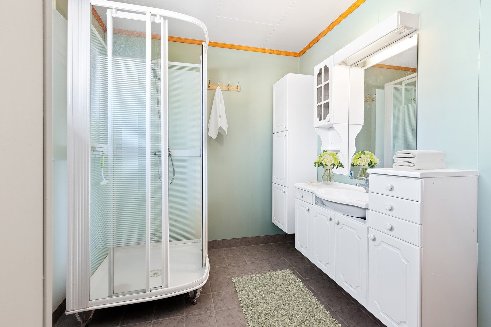 Badet har lys innredning med nedfelt servant og skap under, speil med lys over, høyskap, dusjkabinett og toalett. Galleribilde