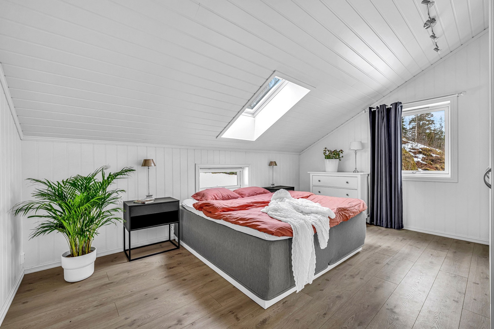 Romslig hovedsoverom innredet med dobbeltseng med nattbord på hver side. Galleribilde
