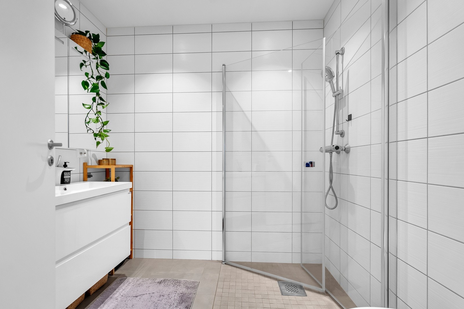 Badet er utstyrt med vegghengt toalett, dusjhjørne og servant med underskap Galleribilde