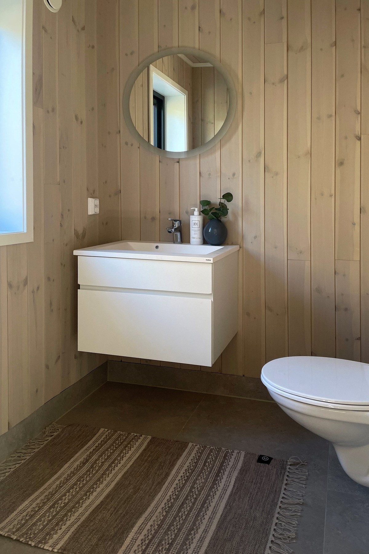 Praktisk toalettrom innredet med servant på underskap og rundt speil. Galleribilde