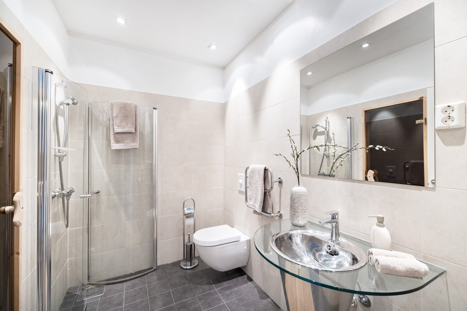 Bad 2 er innredet med vegghengt toalett, servant og dusjhjørne med innfellbare dører Galleribilde