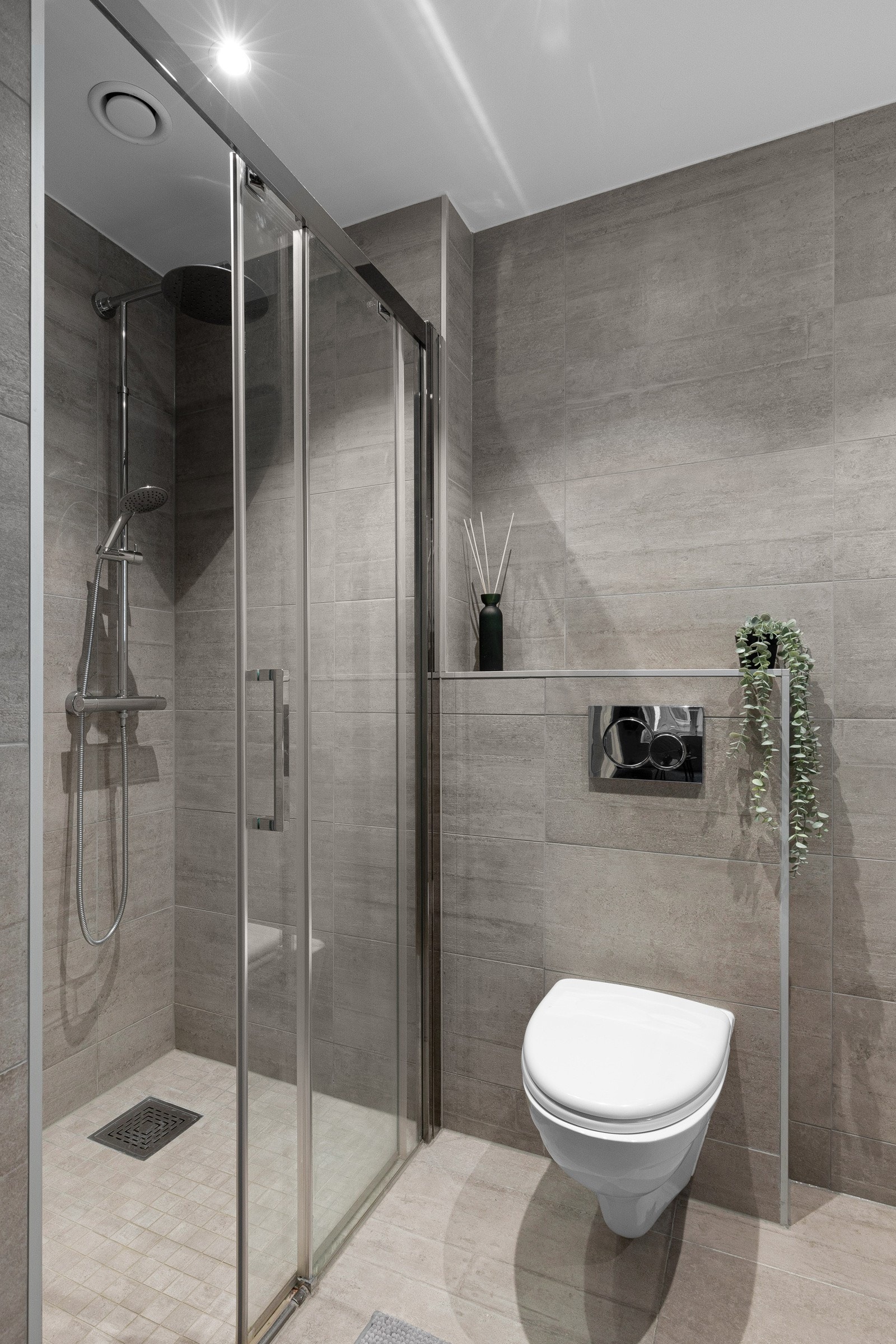 Baderommet inneholder benkeskap med benkeplate, heldekkende servant, veggskap, toalett og dusjhjørne. Galleribilde