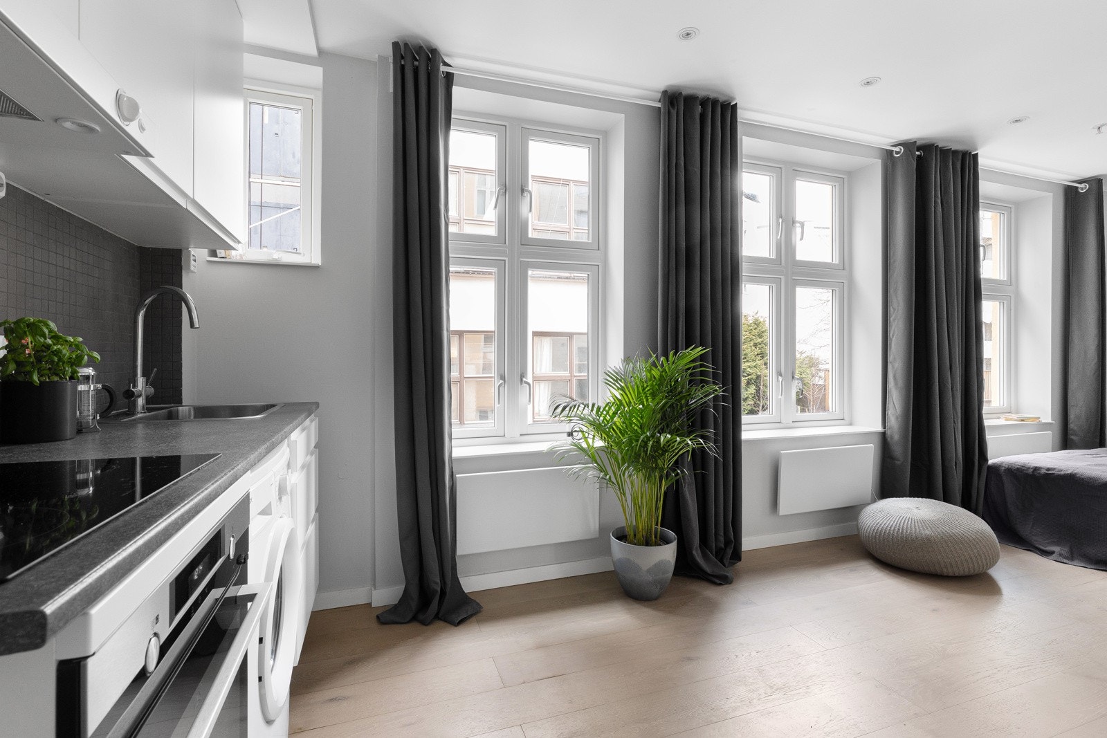 Tidløs kjøkkeninnredning med oppbevaring og integrerte hvitevarer som stekeovn, koketopp, opplegg for vaskemaskin/oppvaskmaskin. Galleribilde