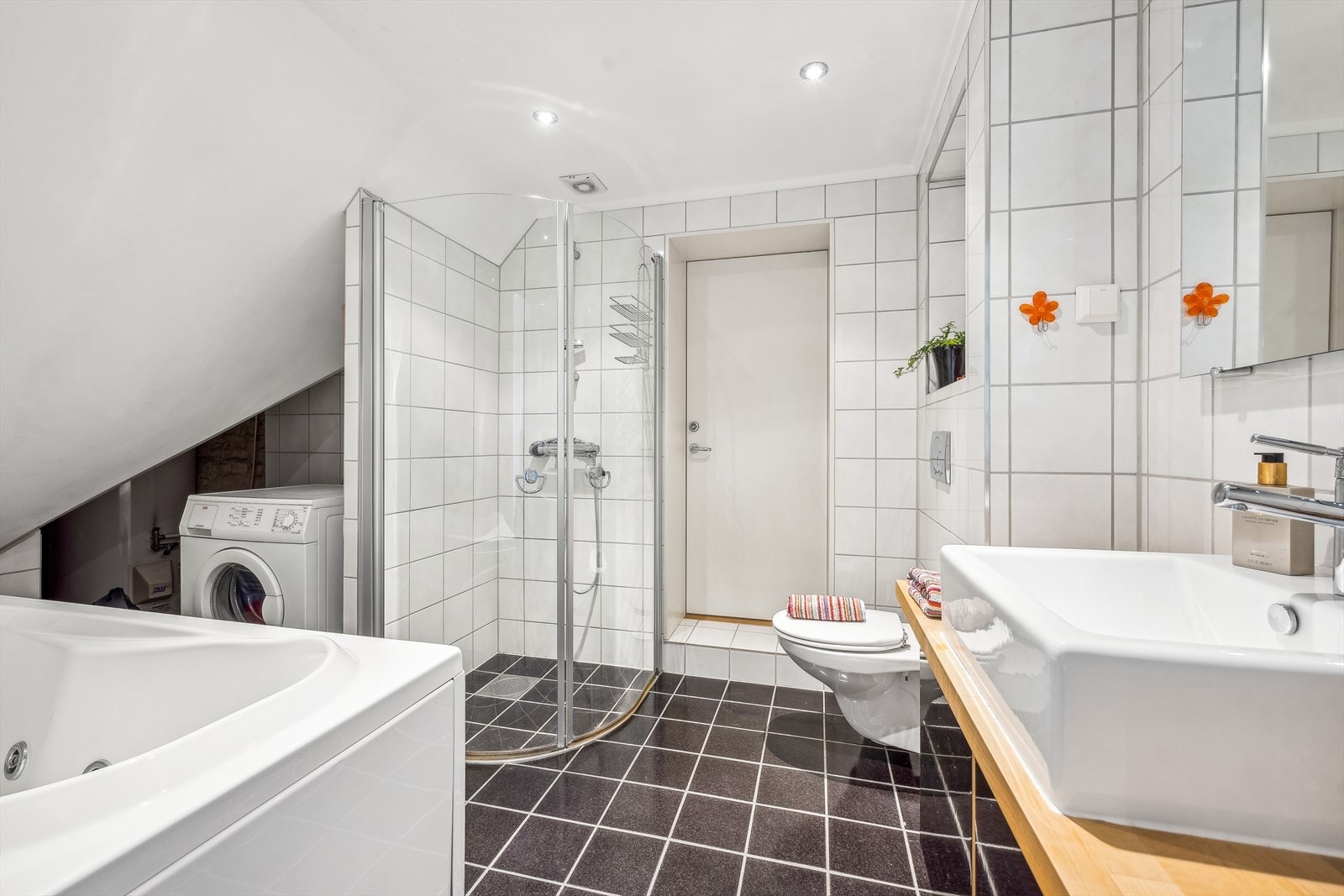 Badet er installert med nedfelt servant, veggmontert toalett, badekar, dusjvegger/hjørne og opplegg for vaskemaskin.Her kan du nyte et lengre bad etter en hektisk arbeidsdag og trekke deg tilbake. Galleribilde