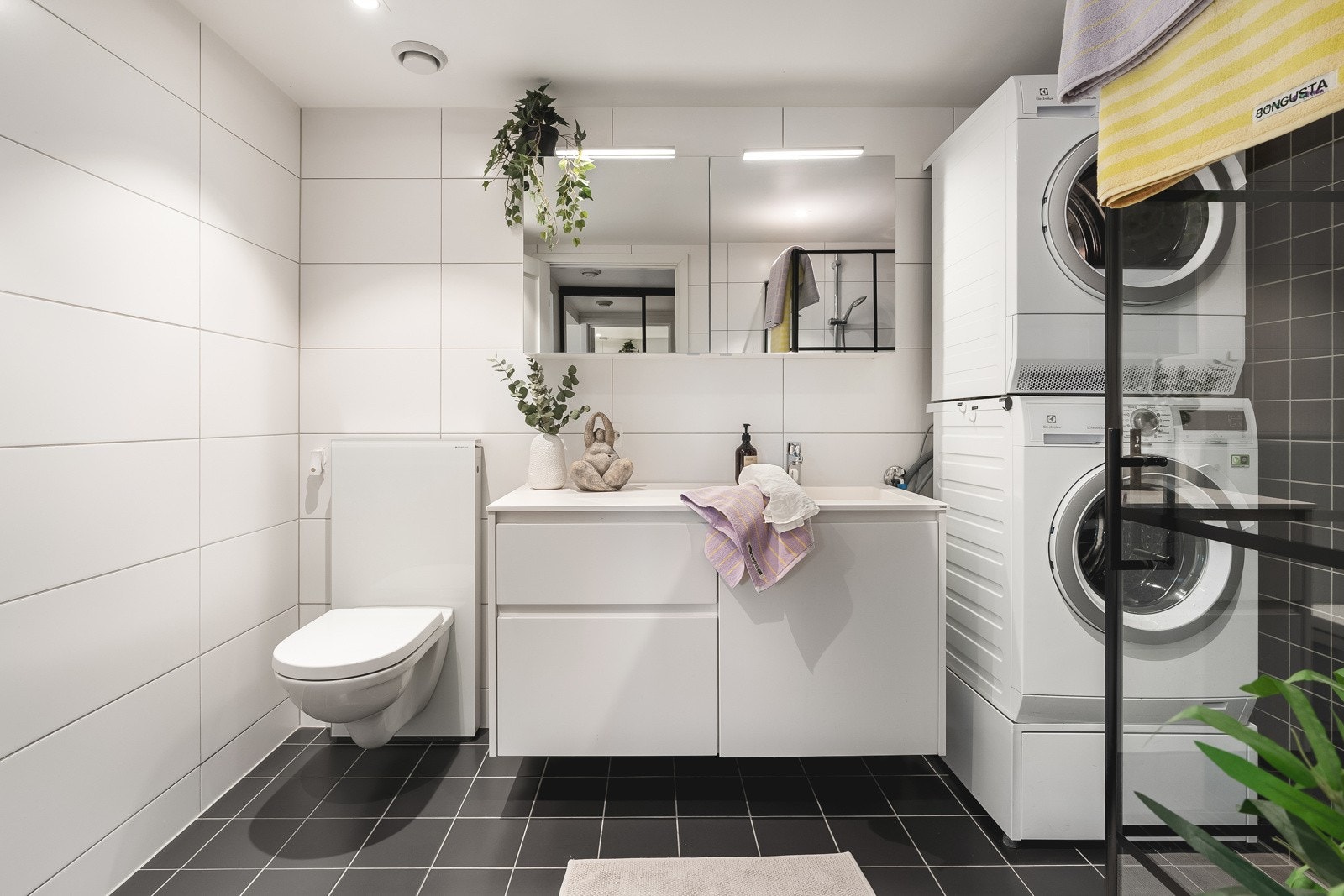 Moderne og flislagt bad med vegghengt wc og opplegg for vaskemaskin og plass for tørketrommel. Galleribilde