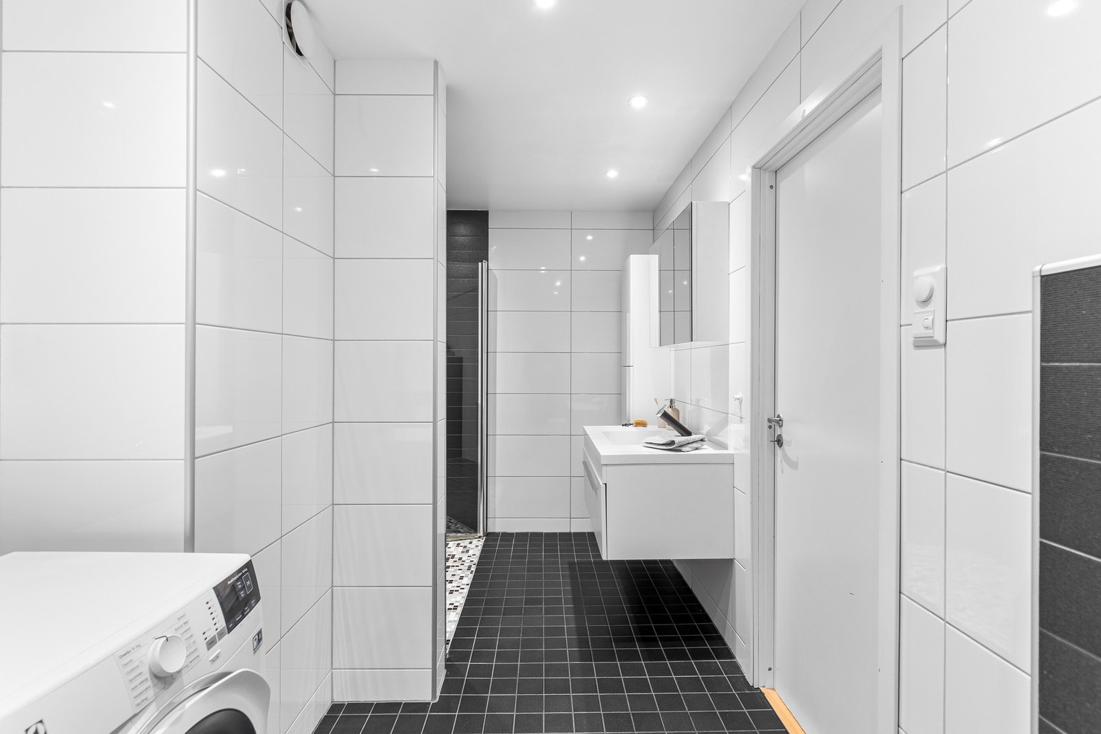 Meget flott sammenslått bad og vaskerom på 8,5 kvm. Badet har moderne kvaliteter som downlights i tak, gulvvarme og en lekker dusjsone med fossefalldusj. Galleribilde