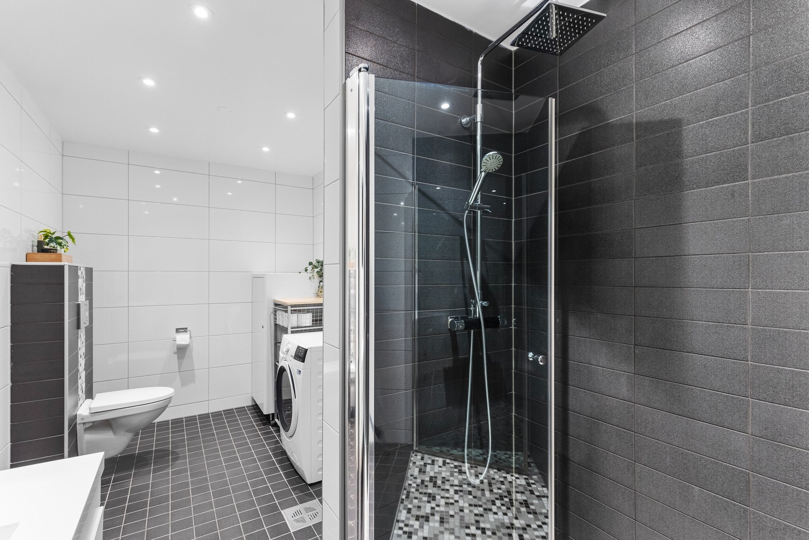 Meget flott sammenslått bad og vaskerom på 8,5 kvm. Badet har moderne kvaliteter som downlights i tak, gulvvarme og en lekker dusjsone med fossefalldusj. Galleribilde