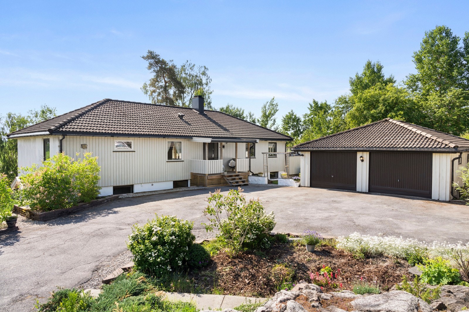 Ved inngangspartiet, på den øvre delen av tomten, er det stor, asfaltert gårdsplass, frittstående dobbelgarasje og en koselig hage opparbeidet i soner. Galleribilde