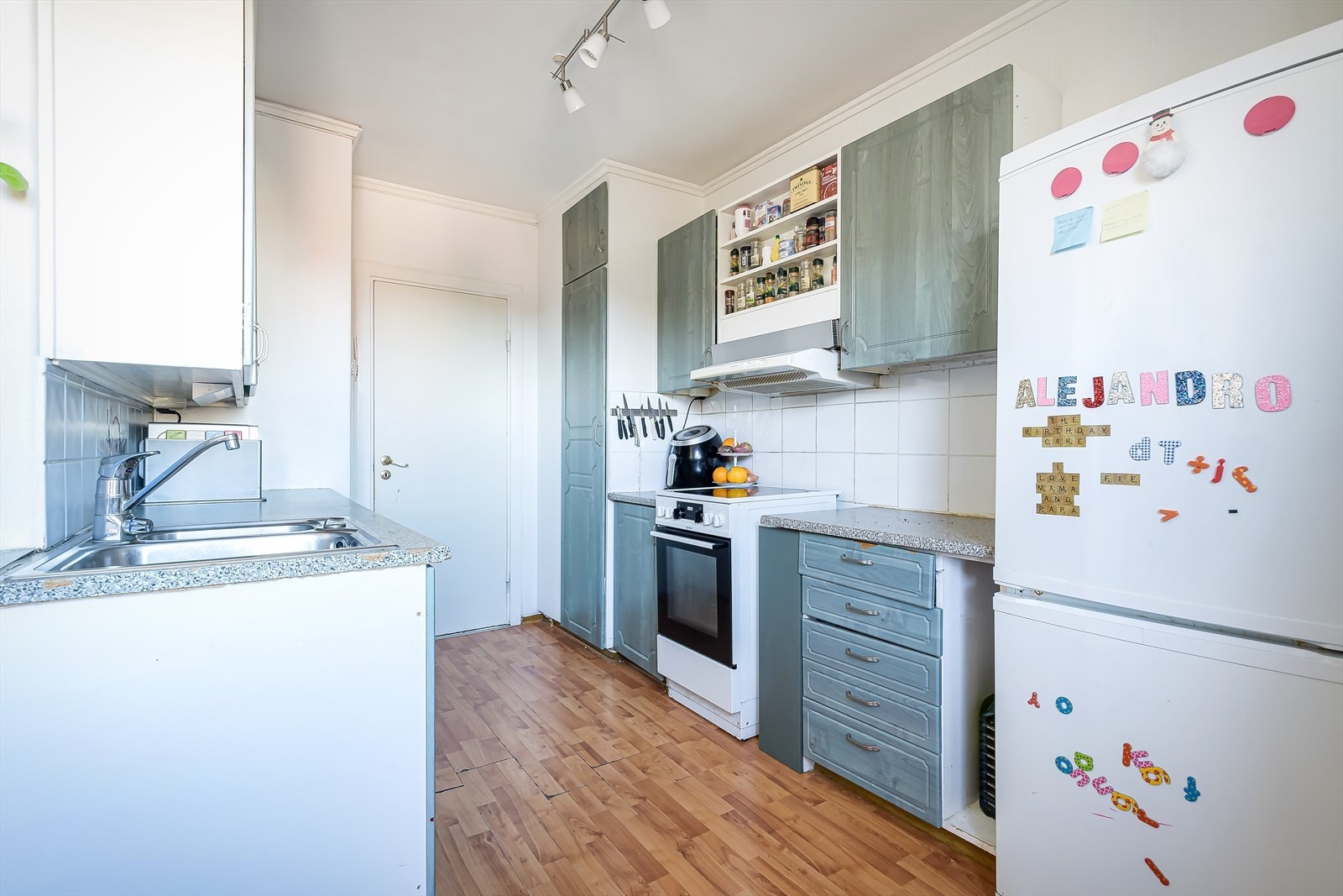 Kjøkkeninnredning med eldre, folierte, profilerte fronter, laminat benkeplate med nedfelt rustfri oppvaskkum samt ettgreps kjøkkenbatteri. Galleribilde