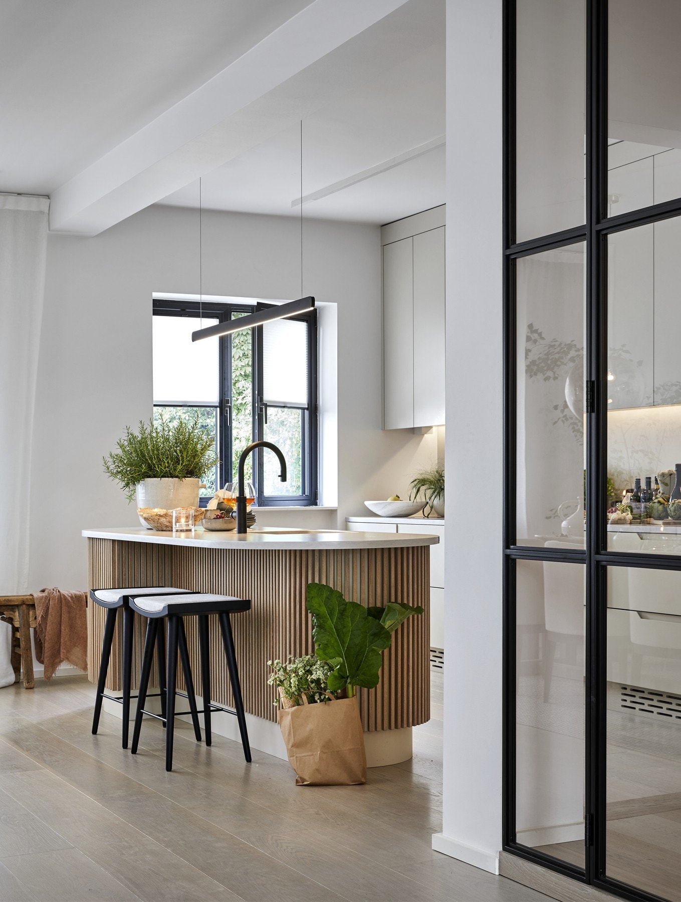 Innredningen har et skandinavisk uttrykk, men er tilført spennende kontrastdetaljer som mørktonet servantarmatur fra Quooker, trespiler og lys benkeplate av Silestone. Kjøkkenøyen er for øvrig unik i sitt slag - spesialdesignet og bygget av den dyktige mø Galleribilde