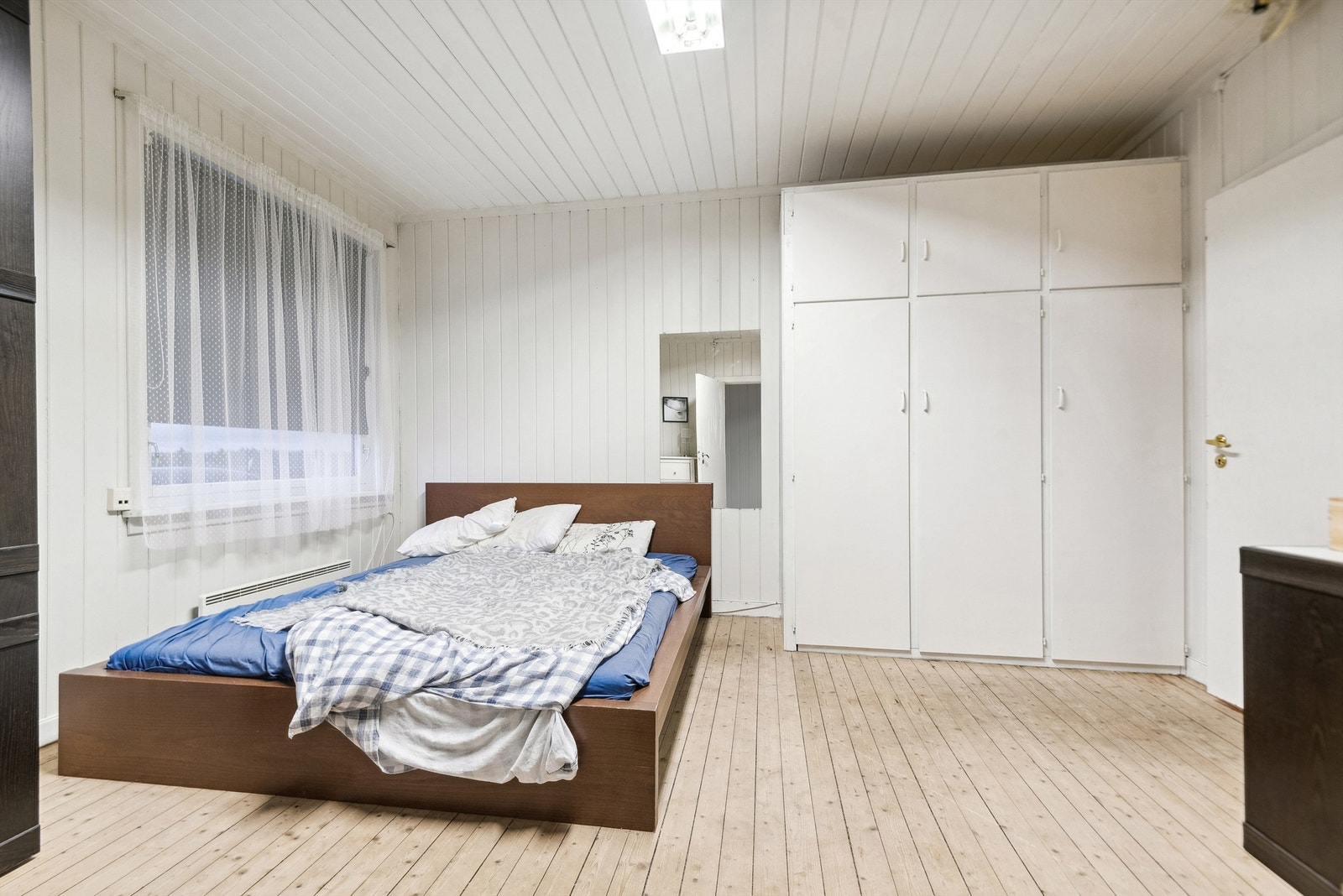 Stort soverom på hovedplan, med tregulv og panelte overfater Galleribilde