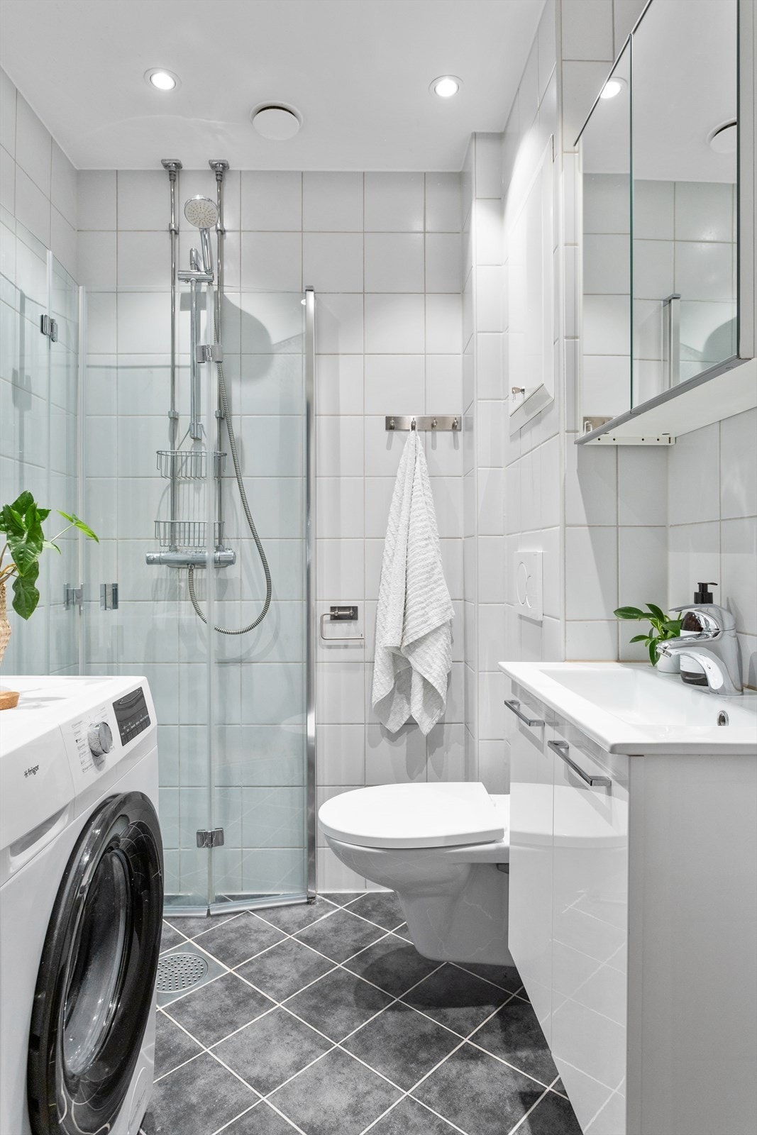 Badet er utstyrt med vegghengt toalett, dusjhjørne med glassvegger, samt innredning med servant og speilskap. Galleribilde