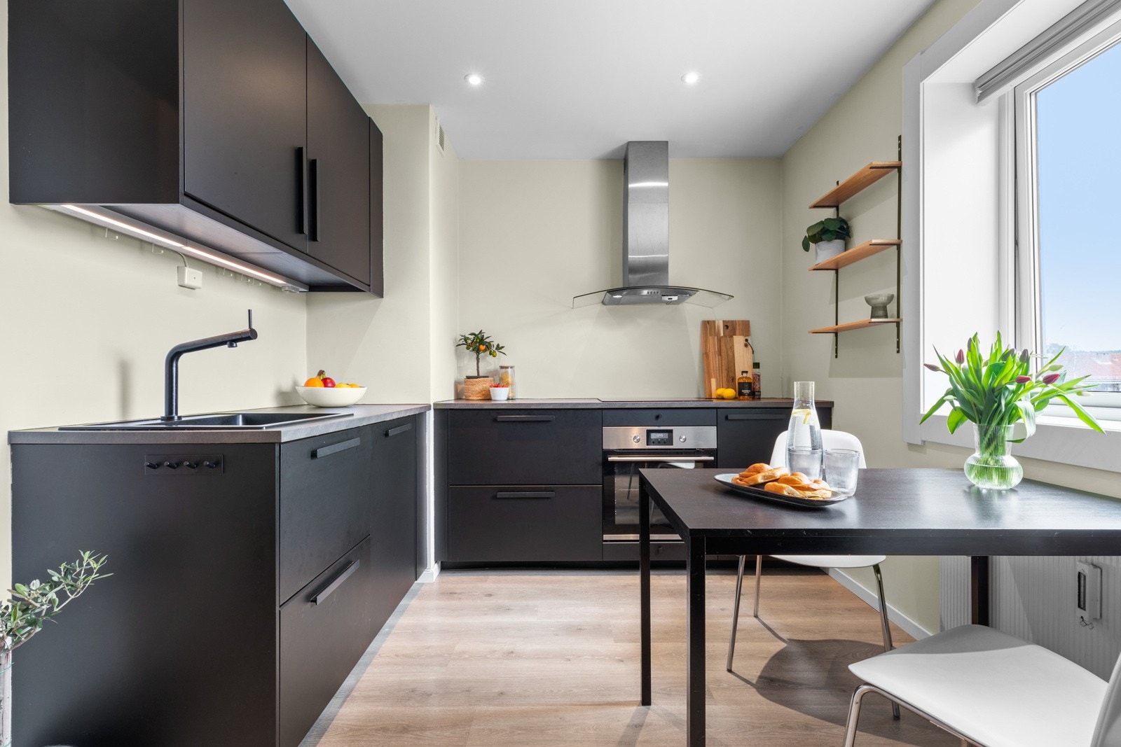 Innredningen fra Ikea har sorte, glatte fronter, sotete glassdører og grå laminatbenkeplate med nedfelt kum i sort kompositt. Galleribilde