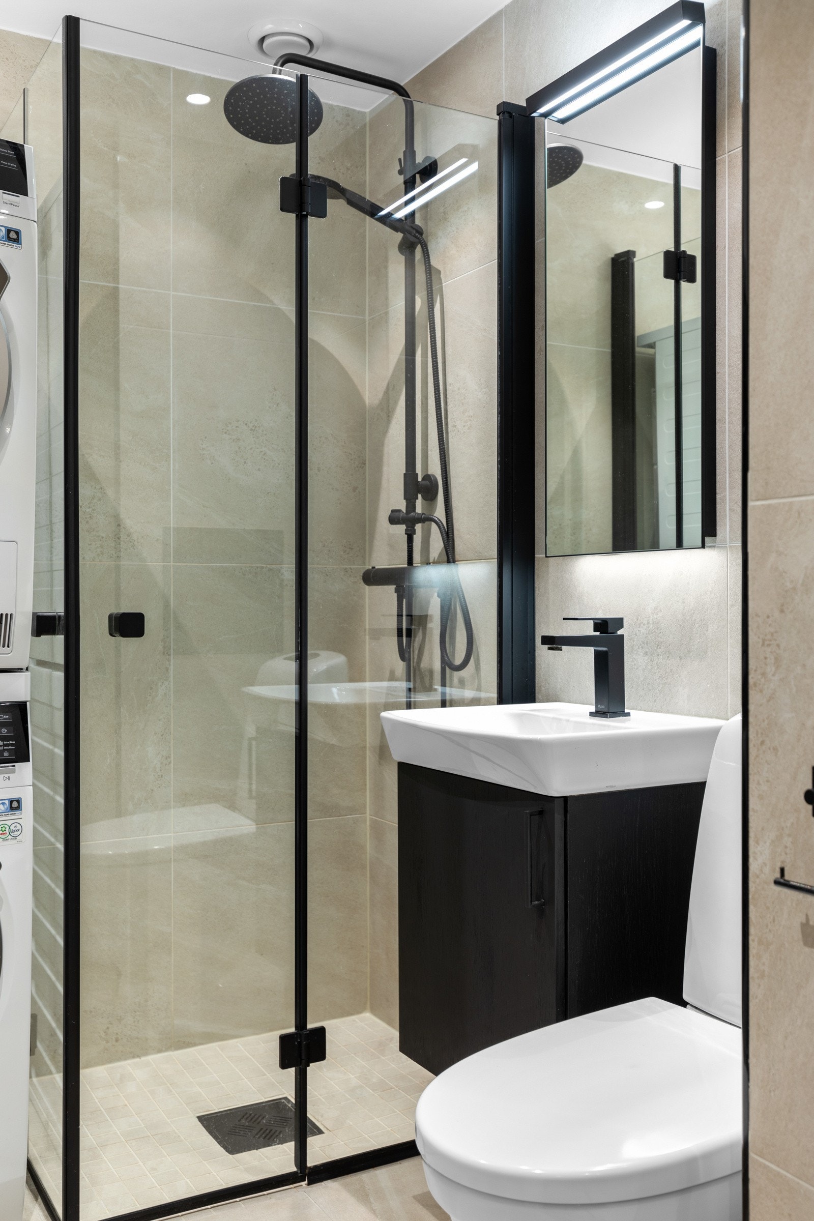 Baderomsinnredningen har sorte fronter og består av en heldekkende servant på en skapseksjon, et høyskap og et speil med belysning. Galleribilde