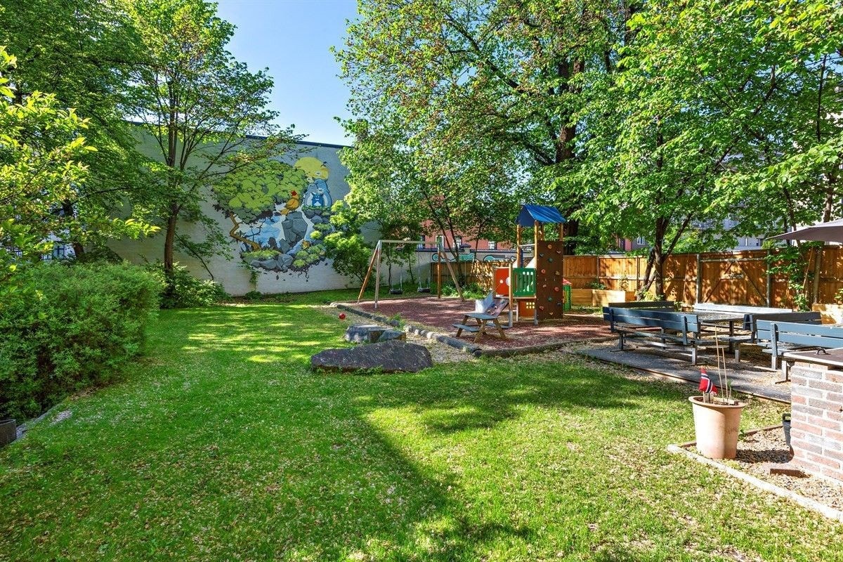 Frodig, flott opparbeidet og skjermet bakgård med beplantning, lekeplass, utegrill og sittemøblement. Galleribilde