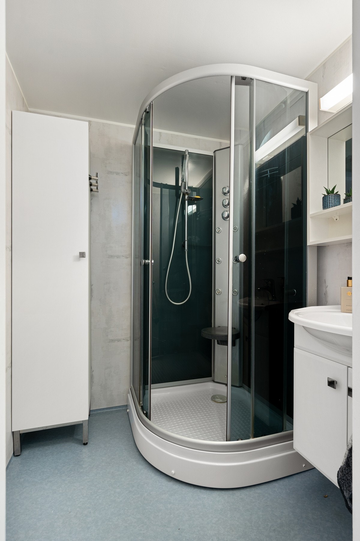 Badet er utstyrt med dusjkabinett, mekanisk avtrekk og servant i skap. Galleribilde