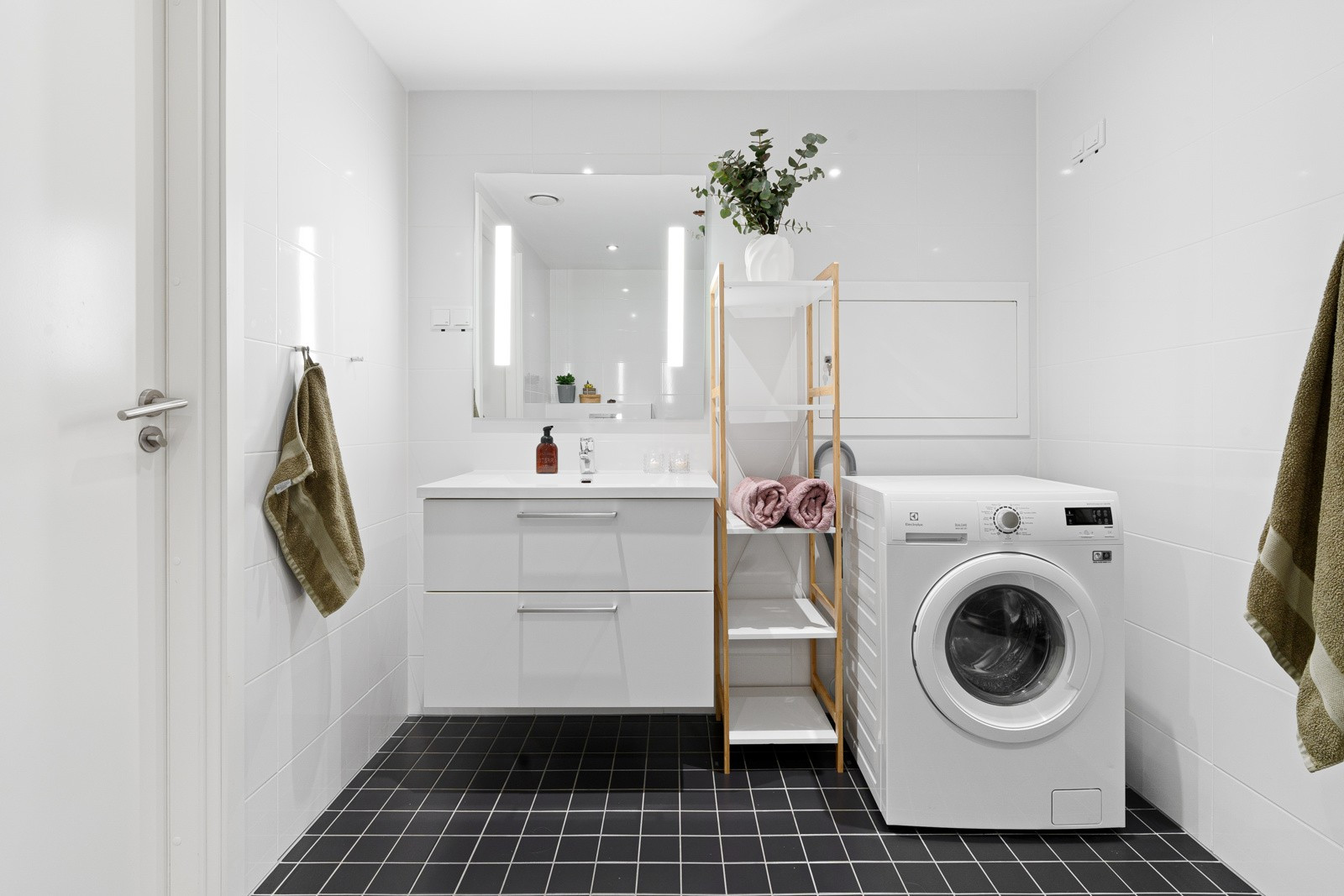 Speil med lys over servant, og opplegg til vaskemaskin som gir enkelhet og bekvemmelighet i hverdagen.