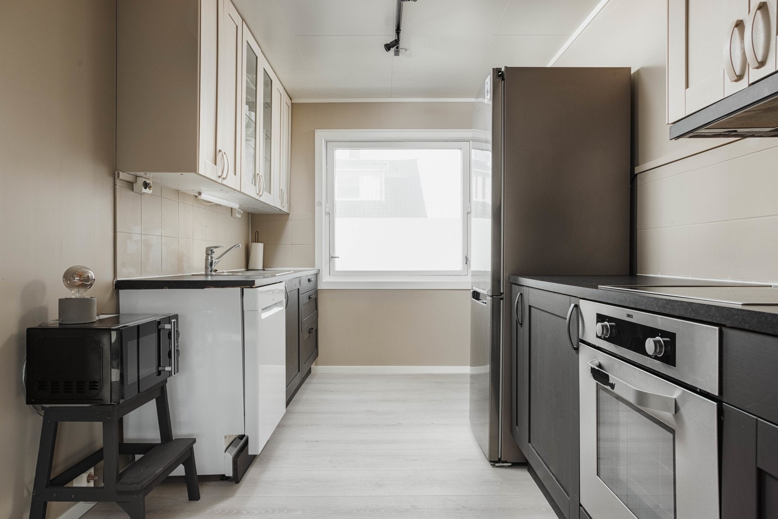 Kjøkkenet som er utarbeidet med skap- og benkeplass. Kjøkkenet står i stil med resten av leiligheten med sine beigemalte vegger og sorte detaljer. Galleribilde