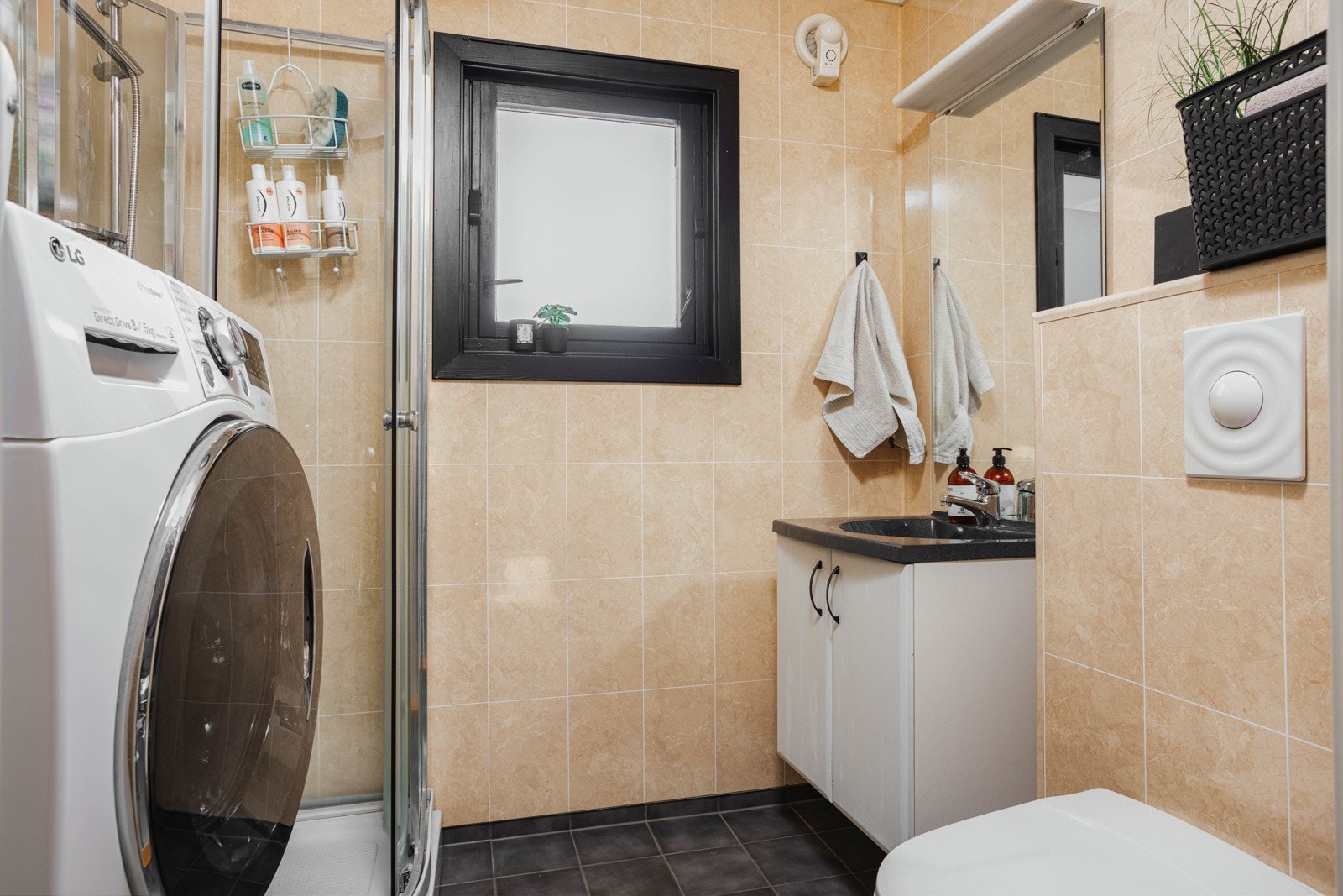 Bad med baderomsinnredning, toalett, dusjkabinett og plass til vaskemaskin. Galleribilde