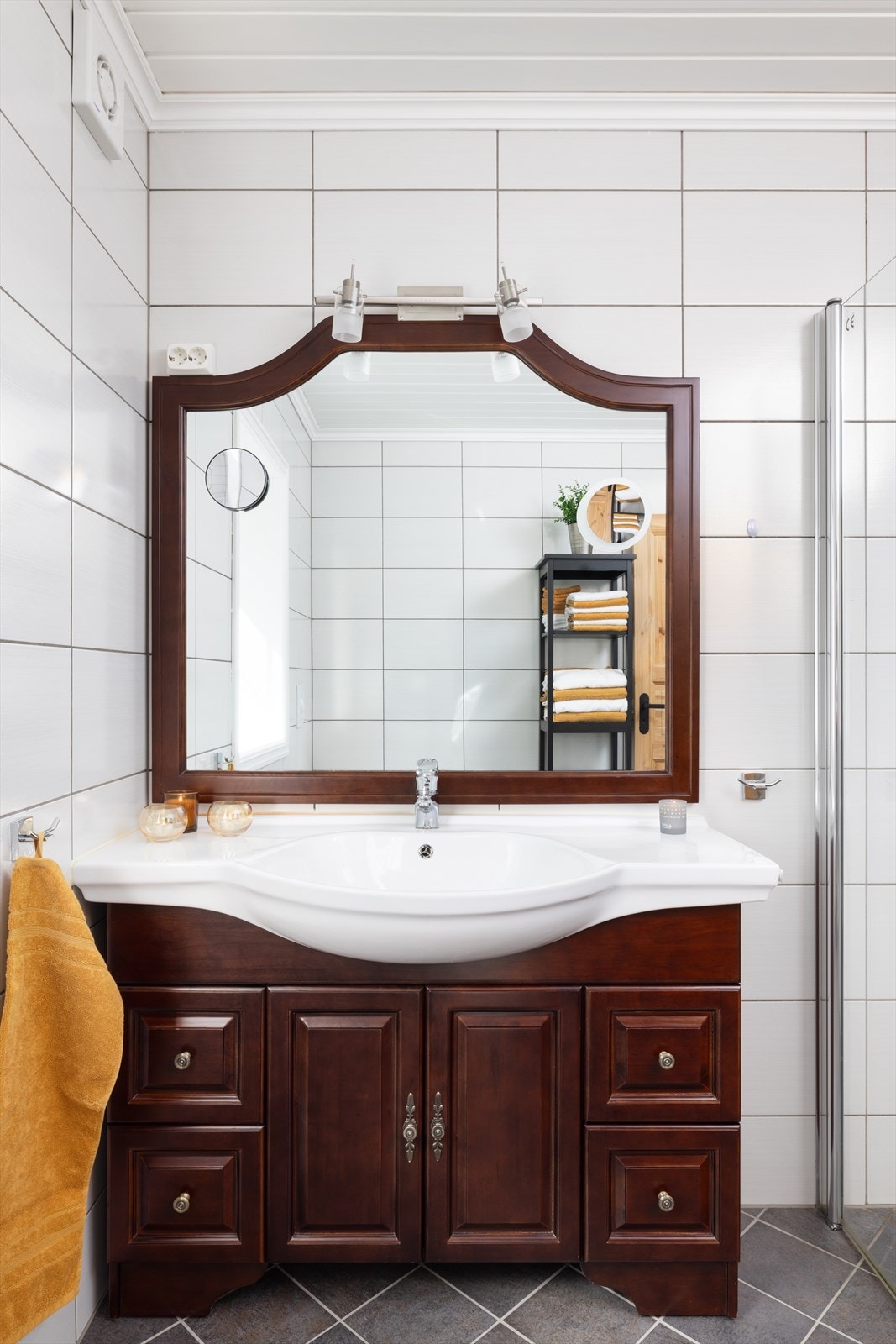 Badet er innredet med servant på innredning, dusjhjørne med glassdører og vegghengt toalett. Galleribilde