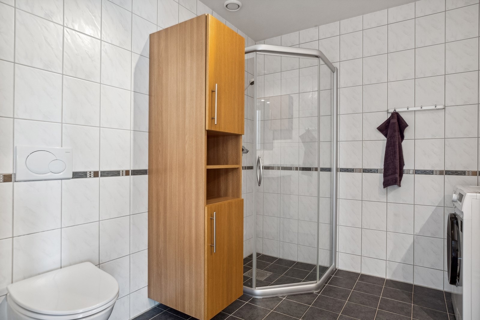 På badet er det vegghengt toalett, dusjhjørne og opplegg for vaskemaskin. Galleribilde