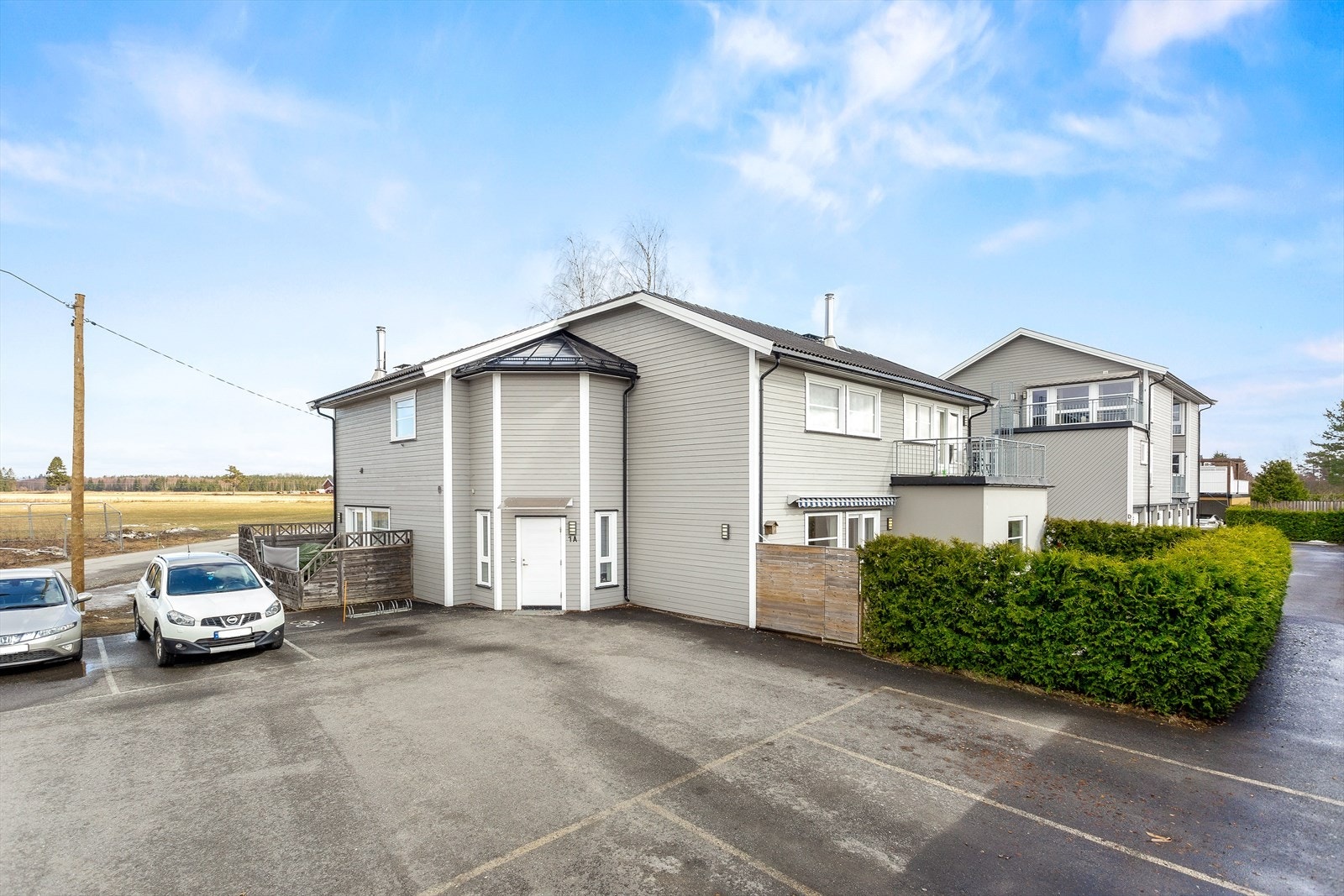 Utvendig fasade som viser inngangsparti og parkeringsplasser for sameiet. Galleribilde