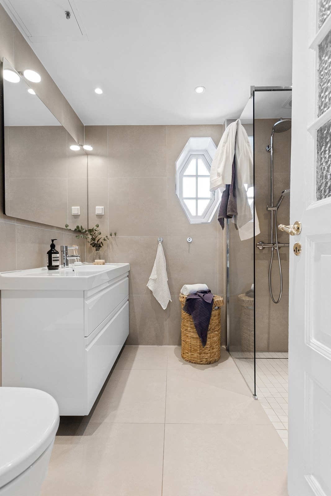 Et pent og delikat baderom fra 2015 som er utstyrt med vegghengt wc, servant med skuffer under og dusj i hjørne med glassvegg. Galleribilde