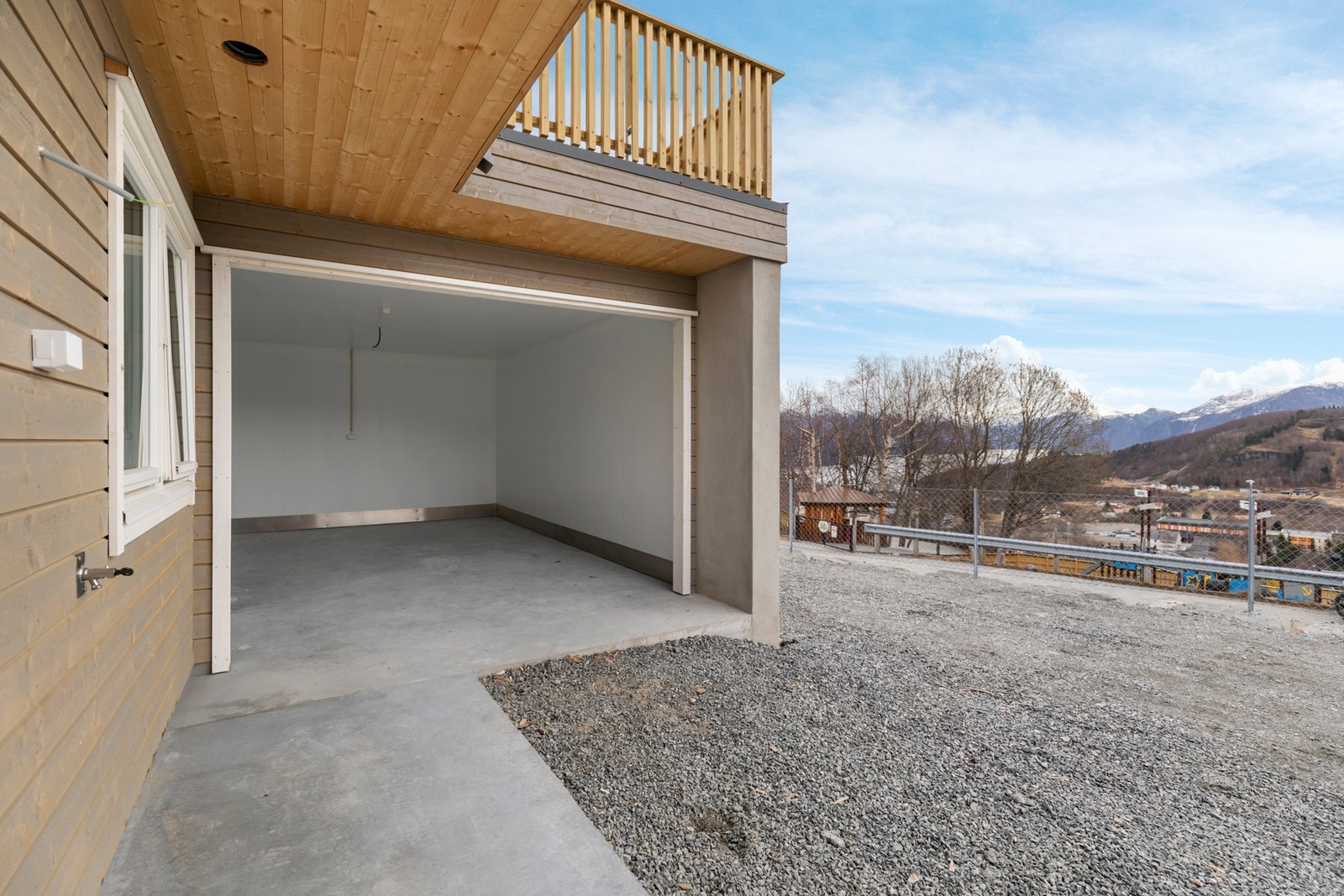 Det er oppført tilknyttet garasje med tett tak over både tilkomst og inngangspartiet slik man kan gå tørrskodd hele året Galleribilde