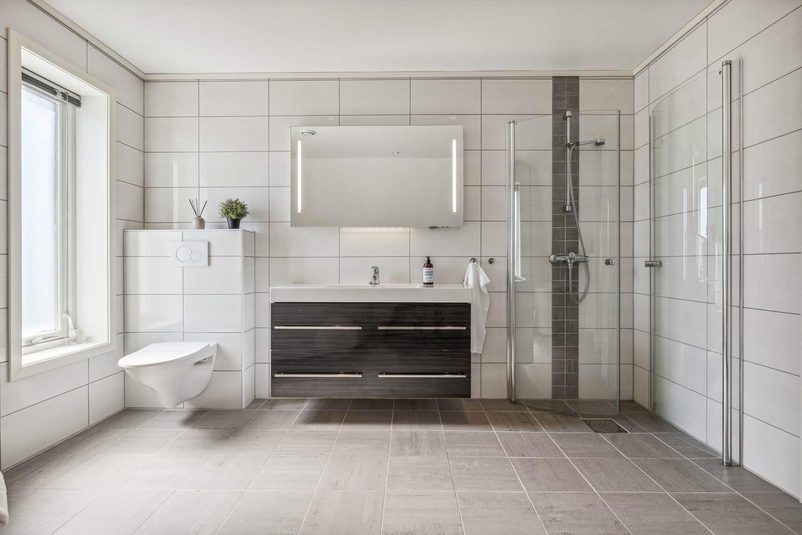 Badet er innredet med Servant med møblement/speil, vegghengt toalett, badekar og innfellbart dusjhjørne. Galleribilde